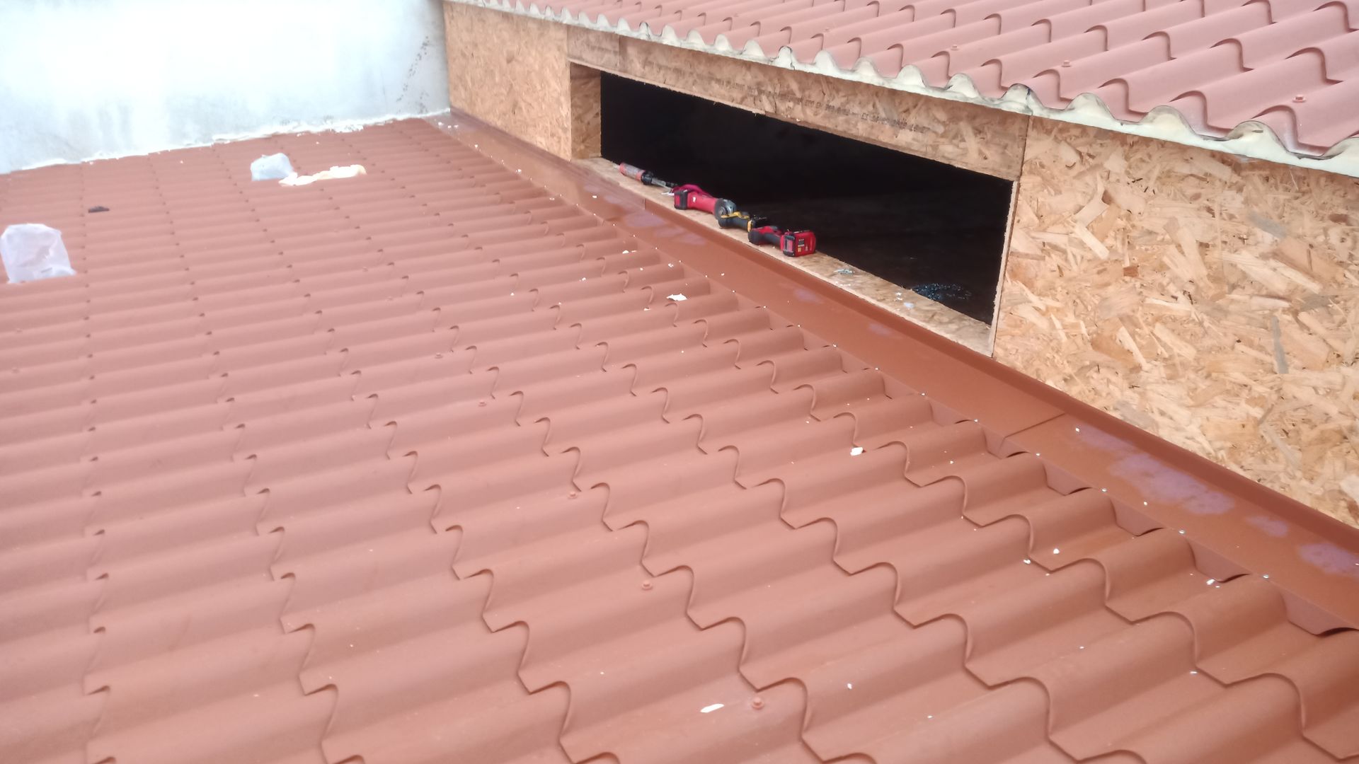 Telhado de telhas vermelhas com uma abertura; a estrutura de madeira exposta é visível.