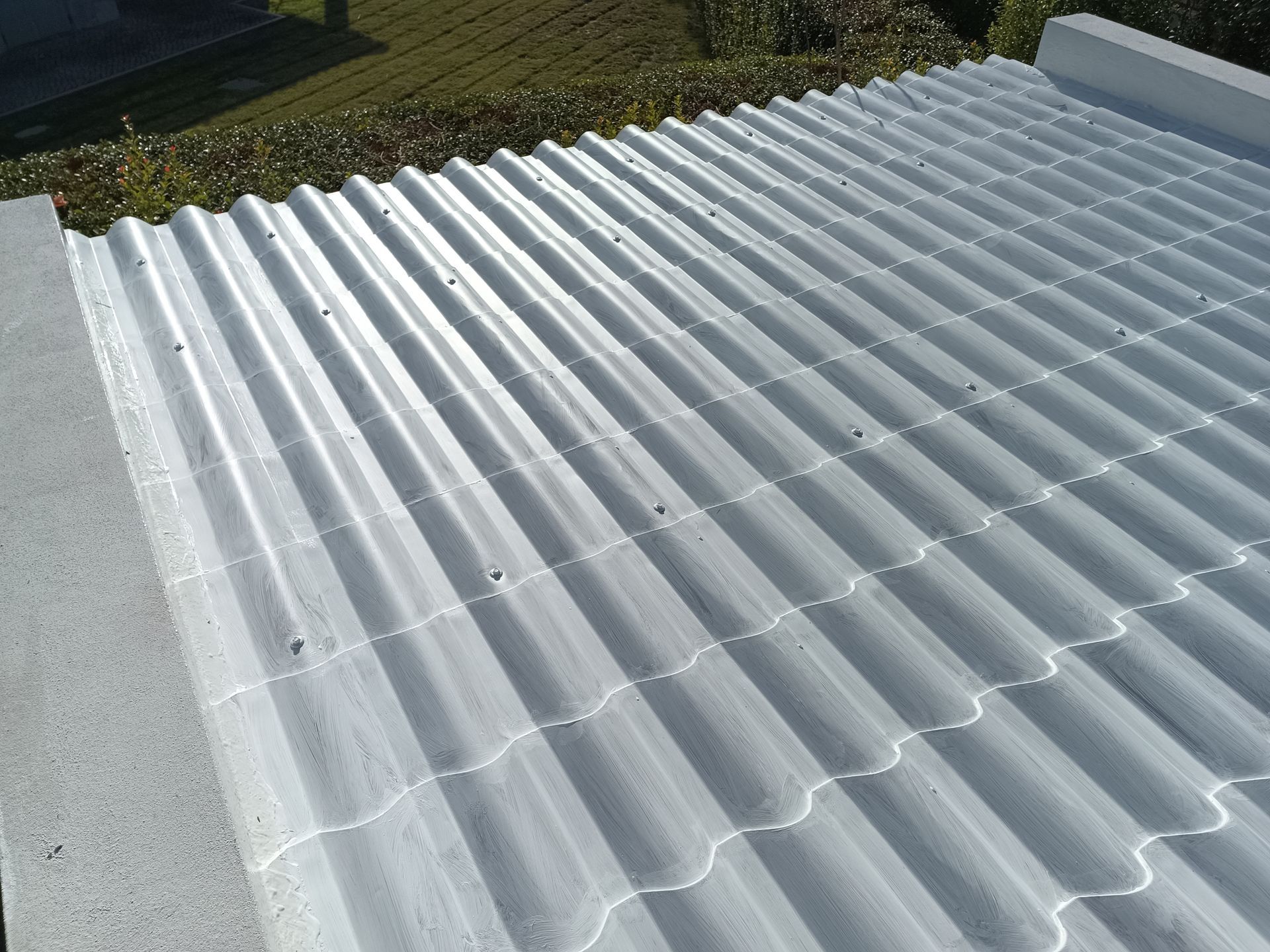 Telhado de metal ondulado branco com borda de concreto.