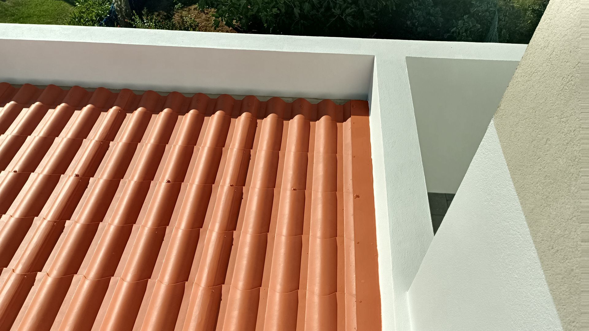 Telhado ondulado marrom com detalhes em branco e uma seção de parede branca.