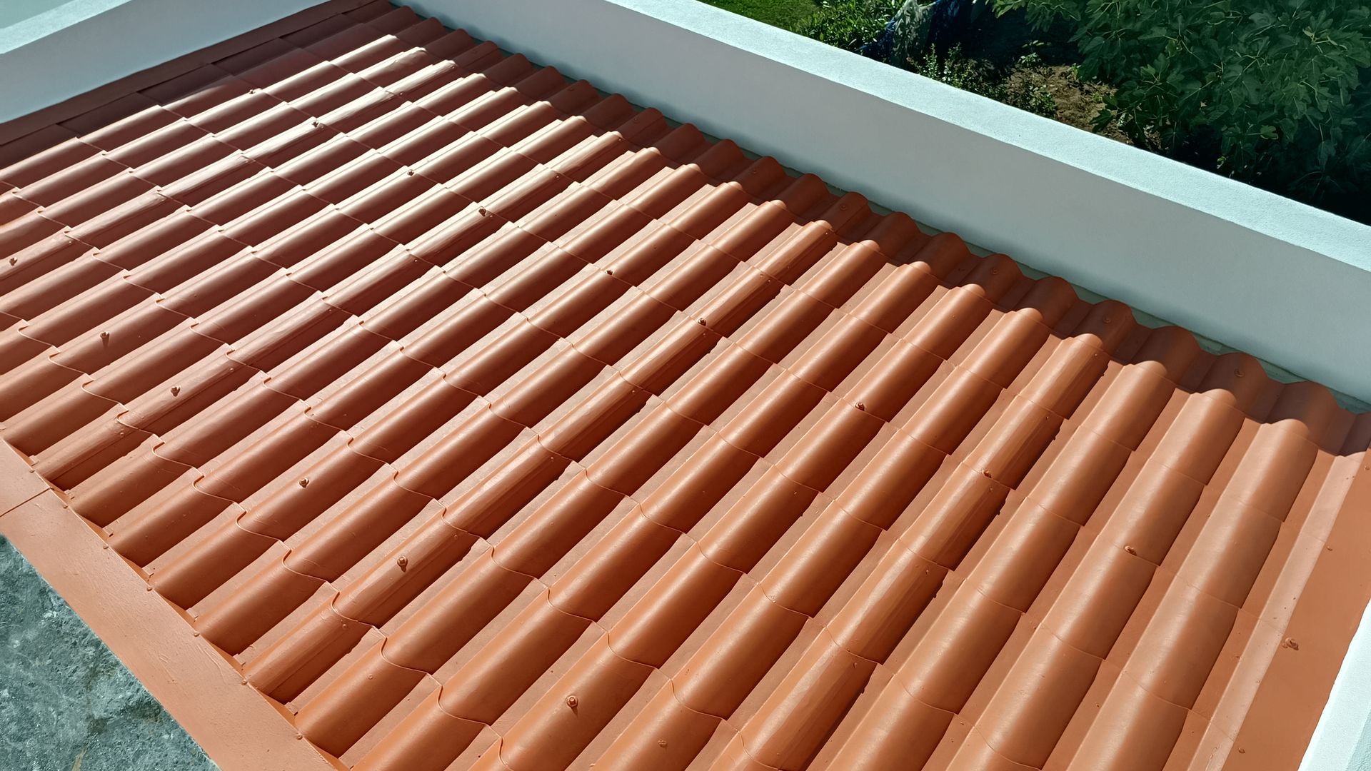 Telhado ondulado laranja em um prédio branco, ambiente externo ensolarado.