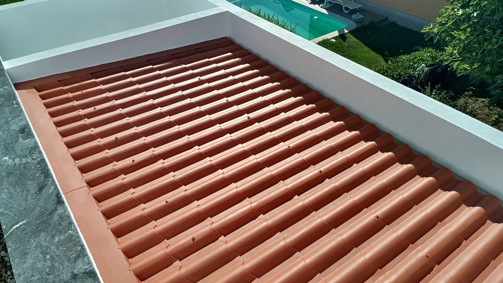 Telhado de terracota ondulada com borda branca, visto de cima.