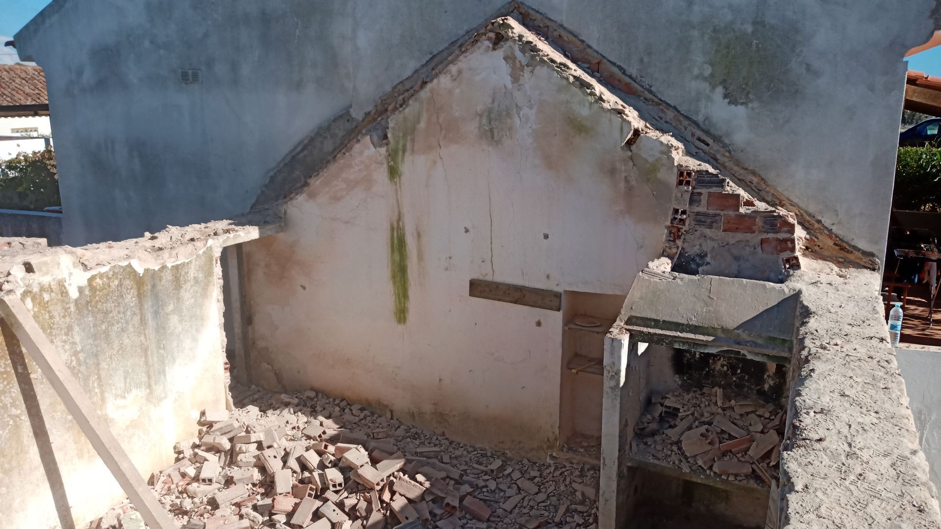 Estrutura de concreto parcialmente demolida com tijolos e entulho expostos.