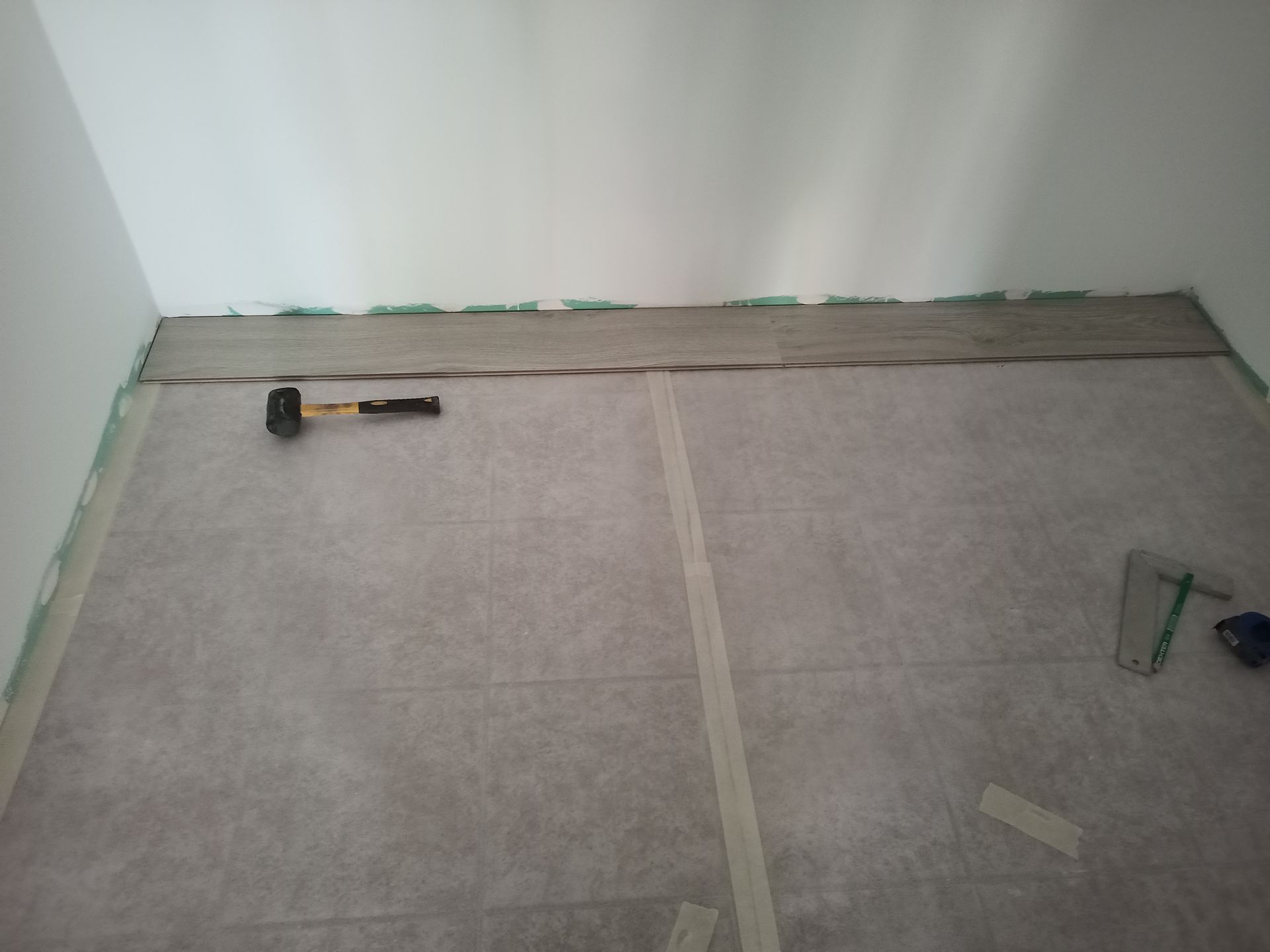 Sala com subpavimento para piso; ferramentas estão sobre ele, perto das paredes.