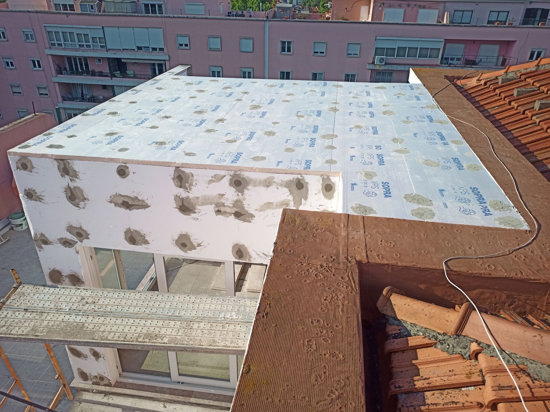 Prédio em construção com isolamento branco no telhado e nas paredes, visto de cima.