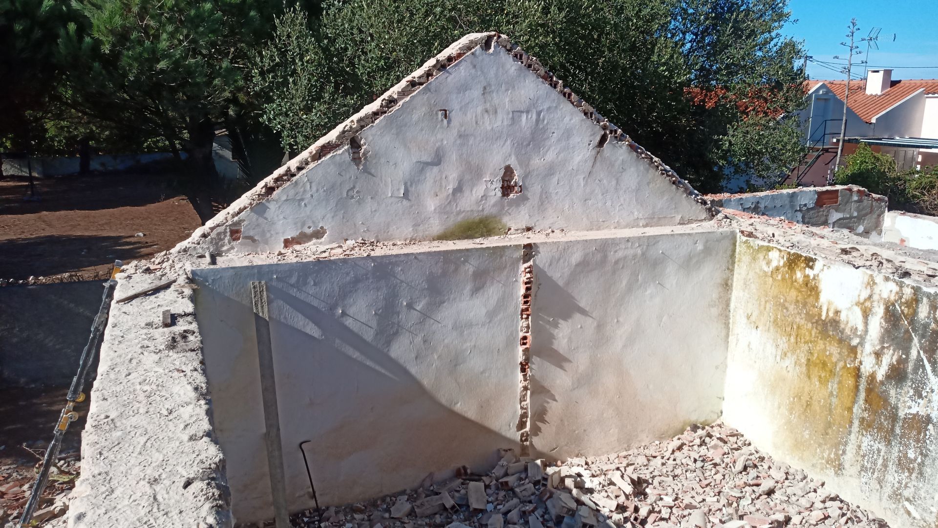 Edifício parcialmente demolido com paredes de tijolo e concreto aparentes, em área externa.