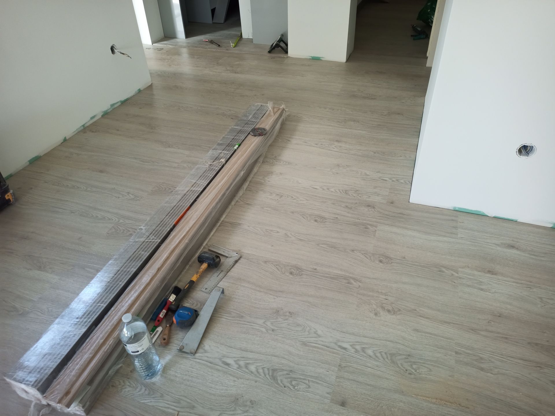 Instalação de piso laminado novo em um cômodo, com ferramentas e materiais necessários.