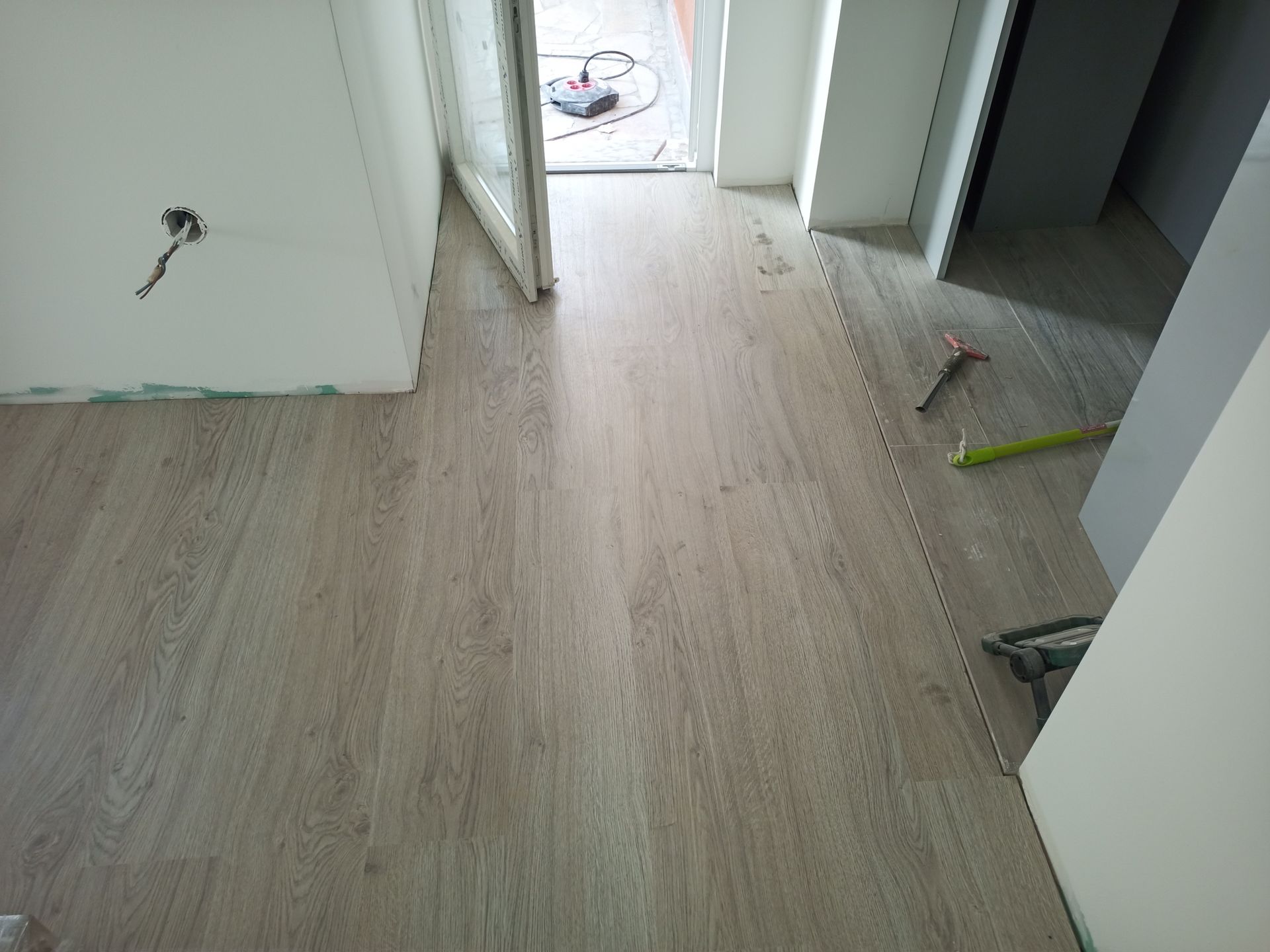 Piso laminado com aparência de madeira clara recém-instalado em um cômodo em construção.