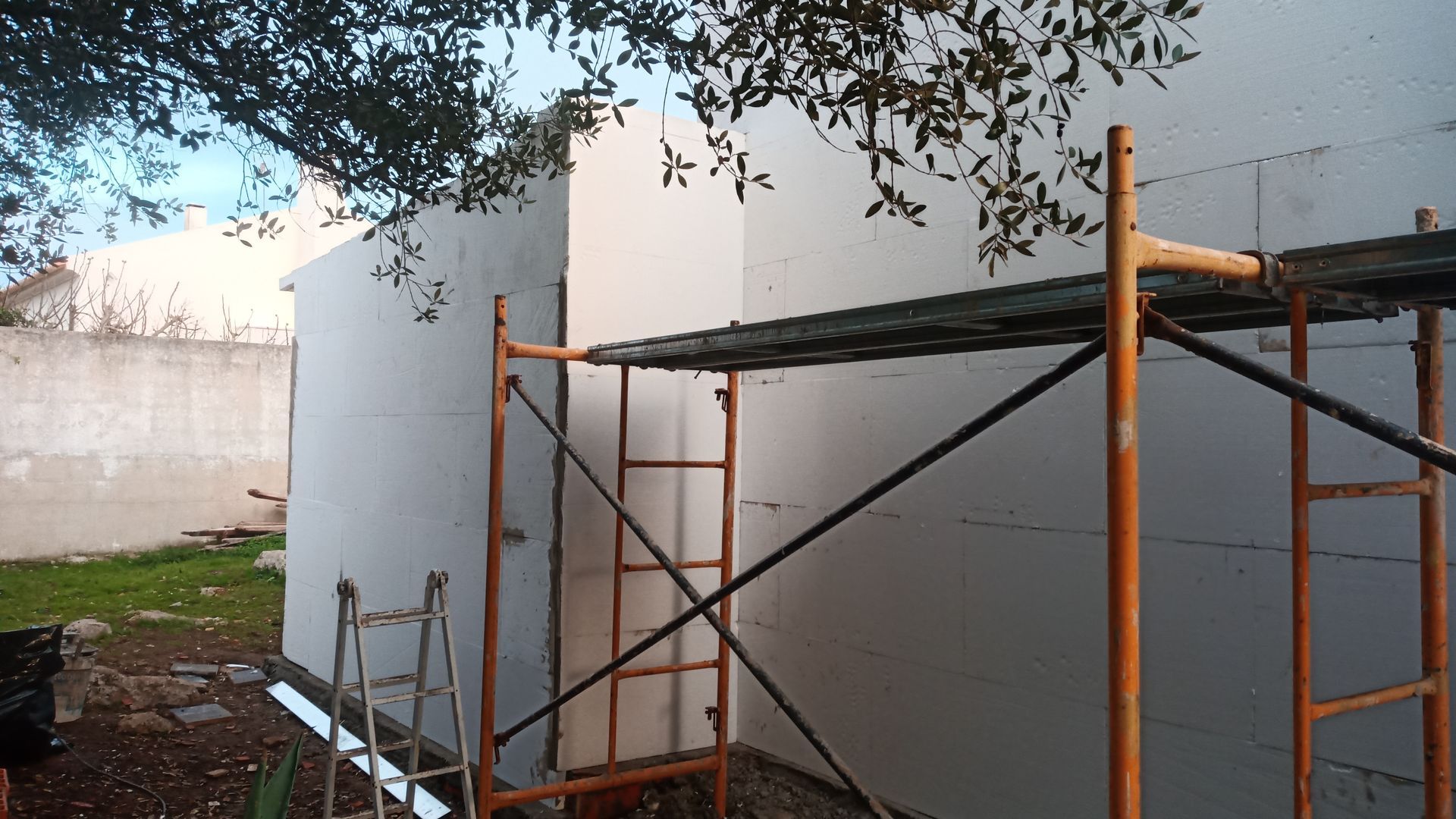 Parede externa em construção com andaimes e isolamento de espuma.