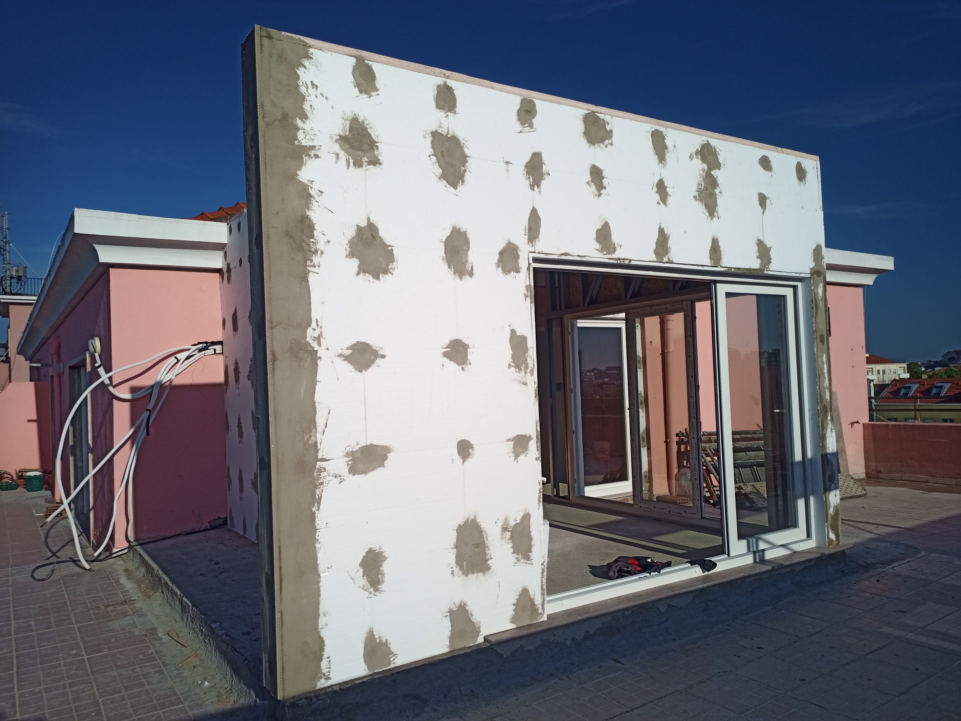 Construção da parede externa de um edifício com uma moldura de janela instalada; a parede é branca com manchas de adesivo cinza.