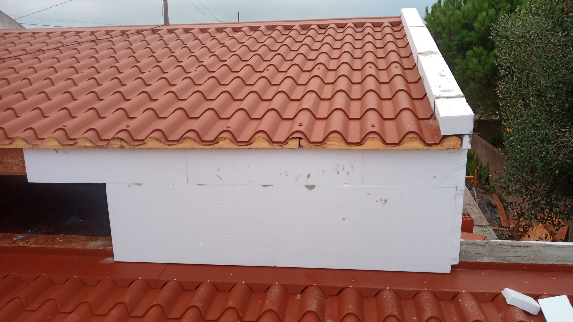 Telhado de telhas vermelhas com estrutura retangular branca.