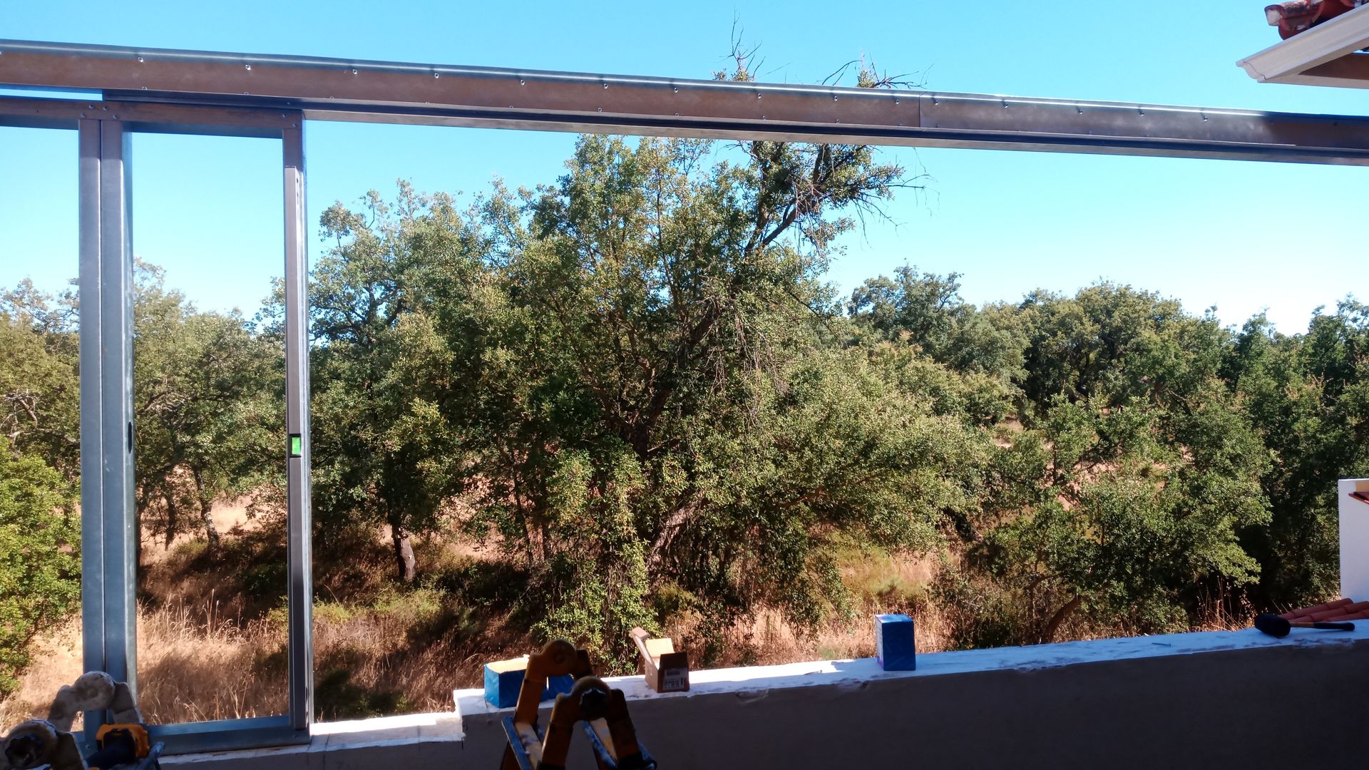 Estrutura de aço em construção com vista para as árvores e o céu.