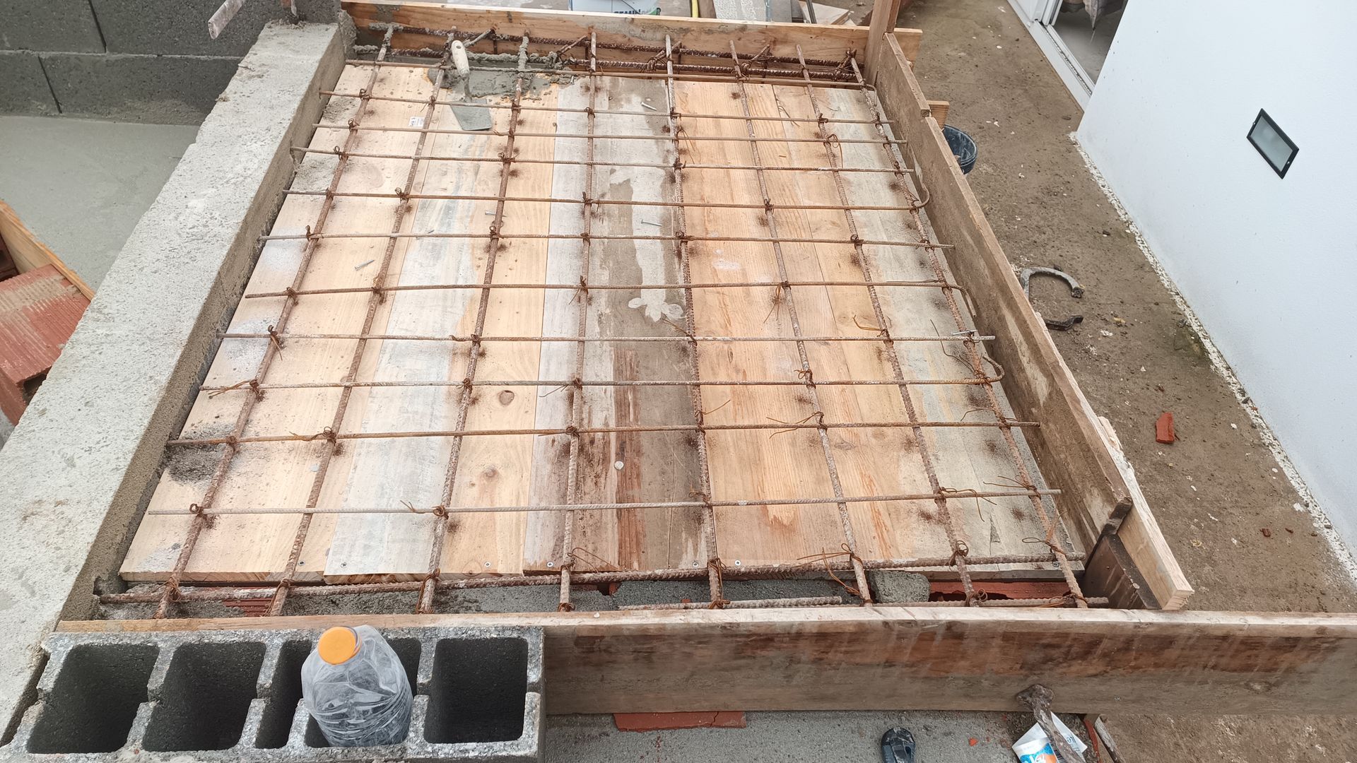 Estrutura de madeira com malha de vergalhões preparada para concretagem em um canteiro de obras.