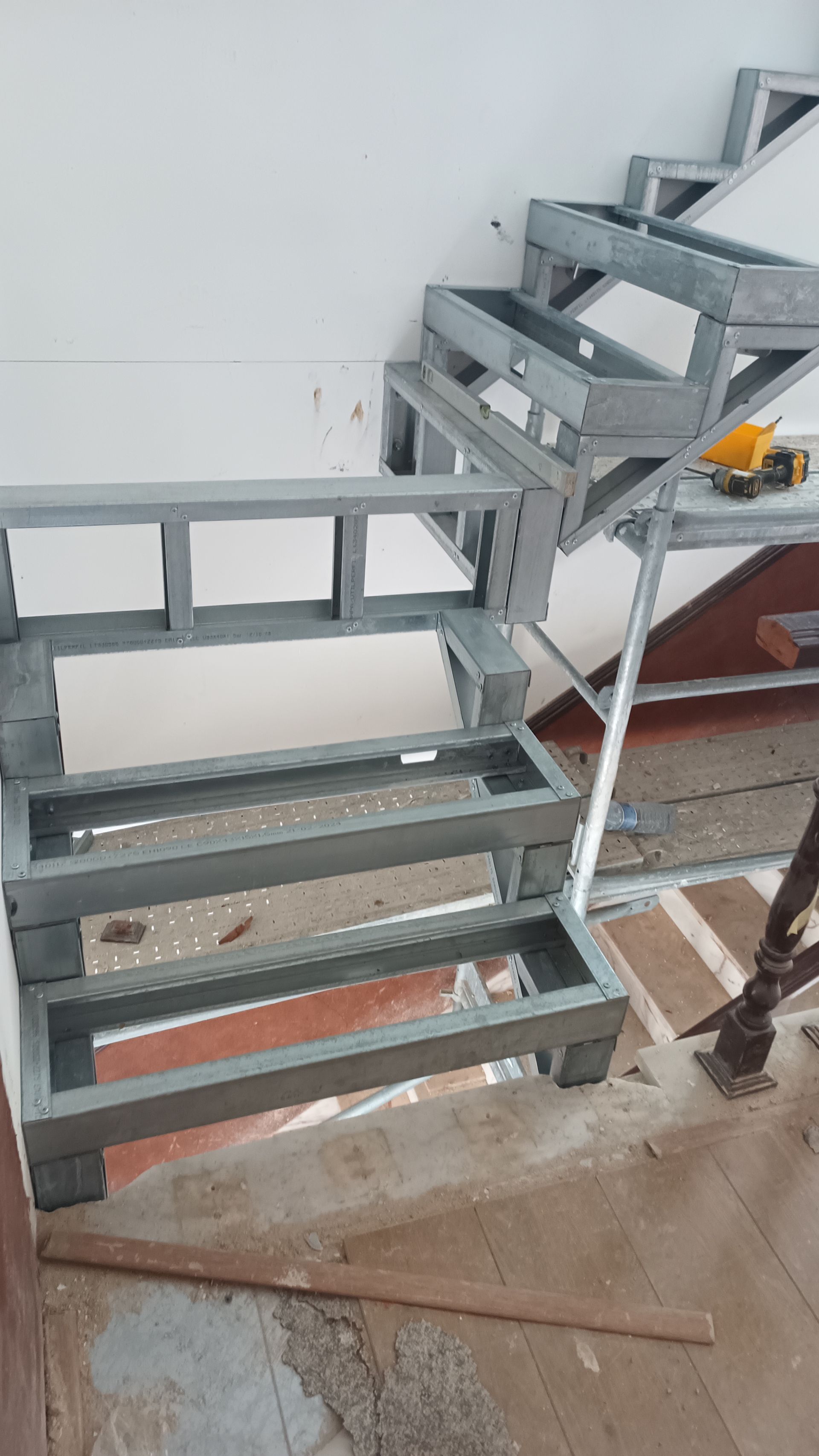 Estrutura metálica de escada em construção, fixada na parede.