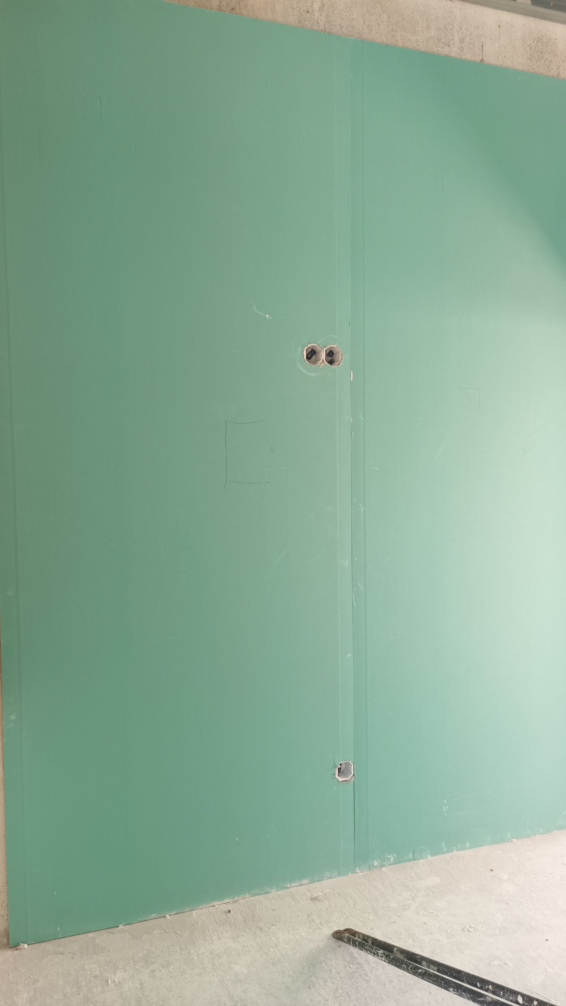 Parede de gesso cartonado verde com tomadas elétricas. Ambiente de construção.