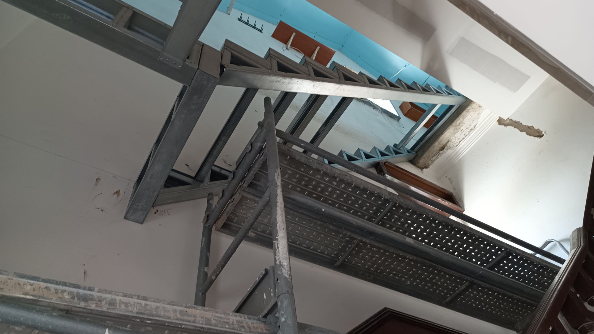 Escada metálica vista de baixo para cima. A luz incide sobre ela.