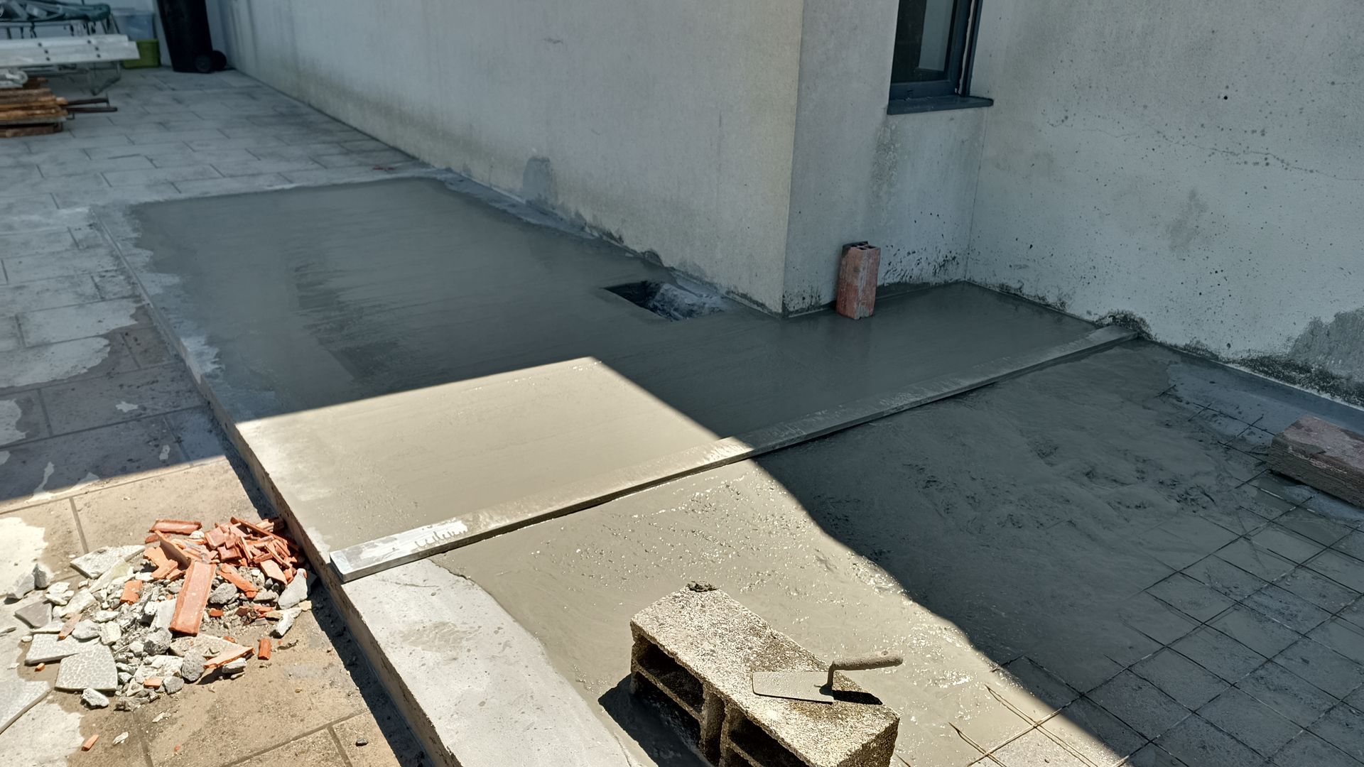 Concretagem sendo despejada para uma passarela ao lado de um prédio. Construção em andamento.