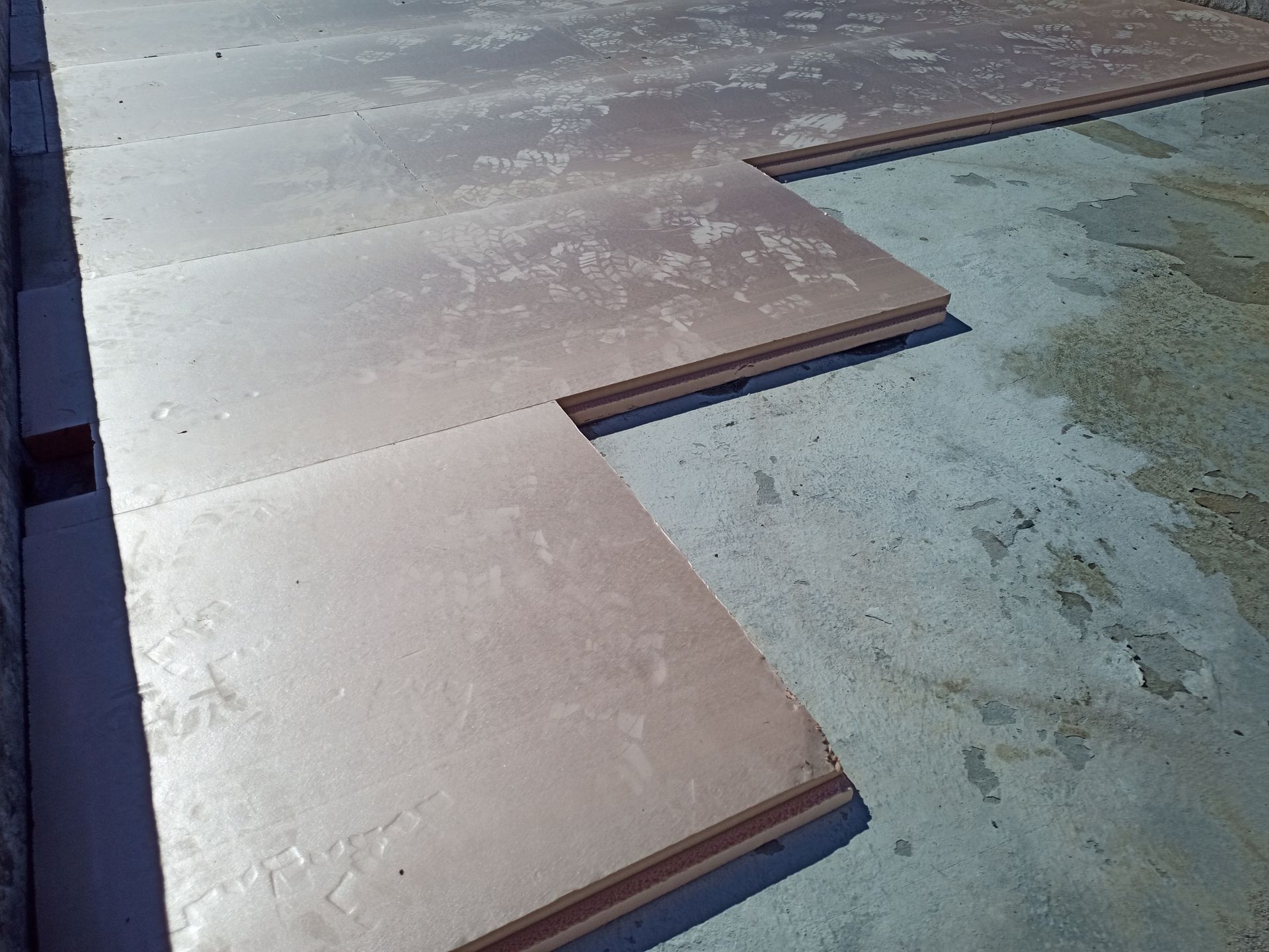 Painéis isolantes marrons cobrindo parcialmente uma superfície de concreto.