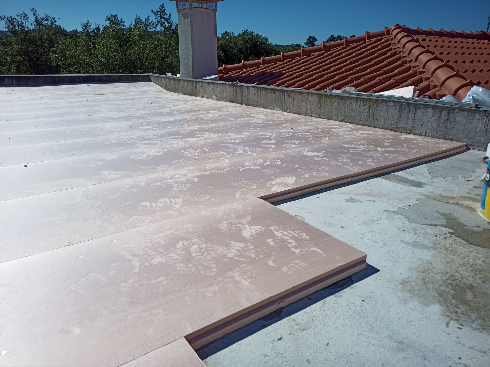 Telhado com placas de isolamento empilhadas, concreto e telhas de terracota.