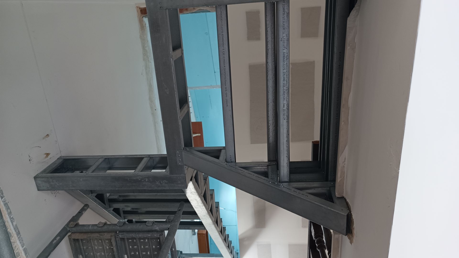 Escada com estrutura de aço em construção, fixada na parede.