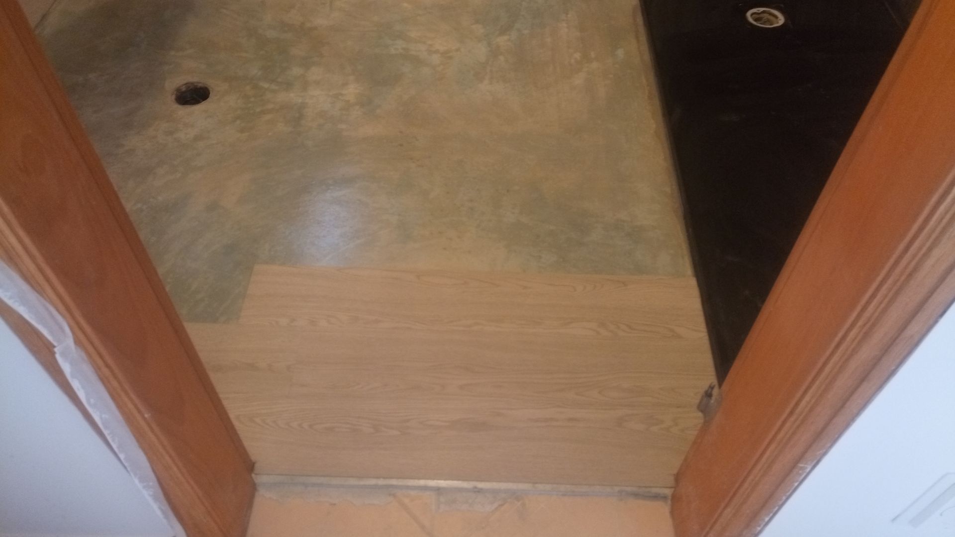 Vista do teto com vigas de madeira marrom, painéis de madeira clara e uma seção escura perto de uma luz embutida.