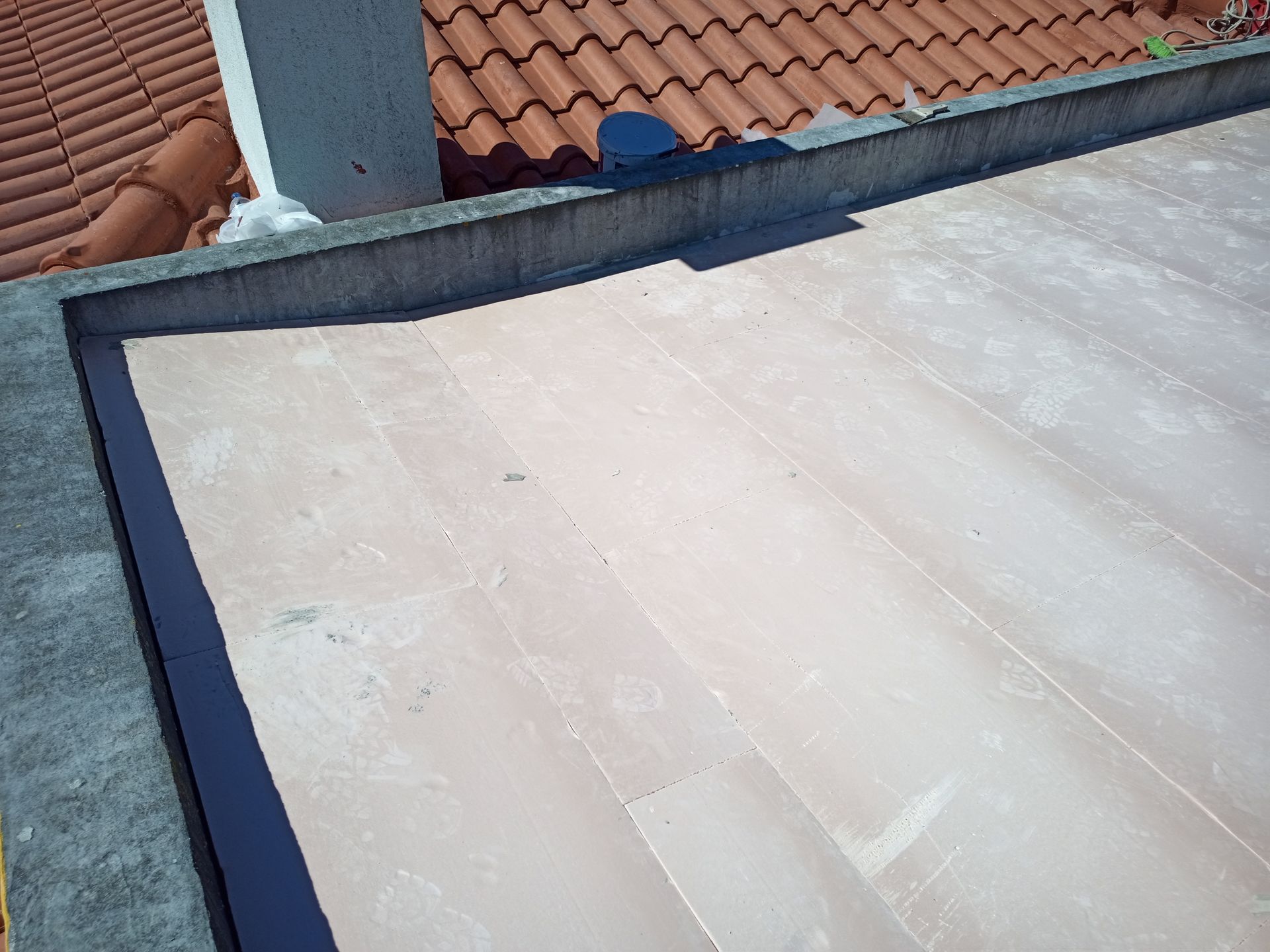 Telhado plano com borda ligeiramente curva, adjacente a um telhado de telha. O telhado plano é de cor bege-rosado claro.