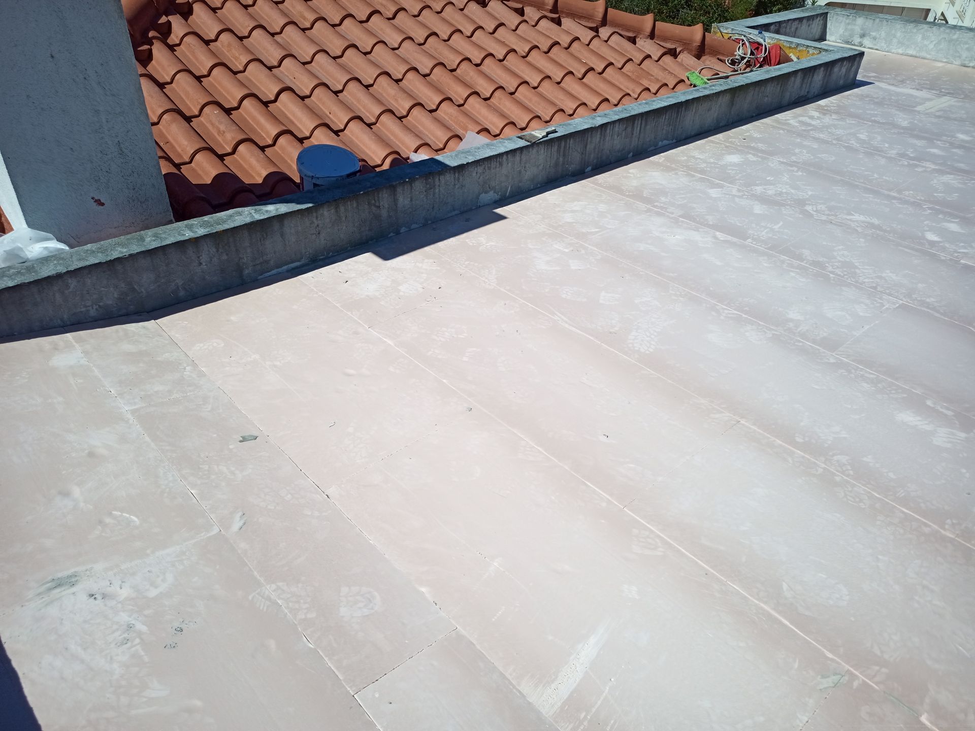 Telhado plano com borda de concreto ao lado de um telhado de telhas de terracota.