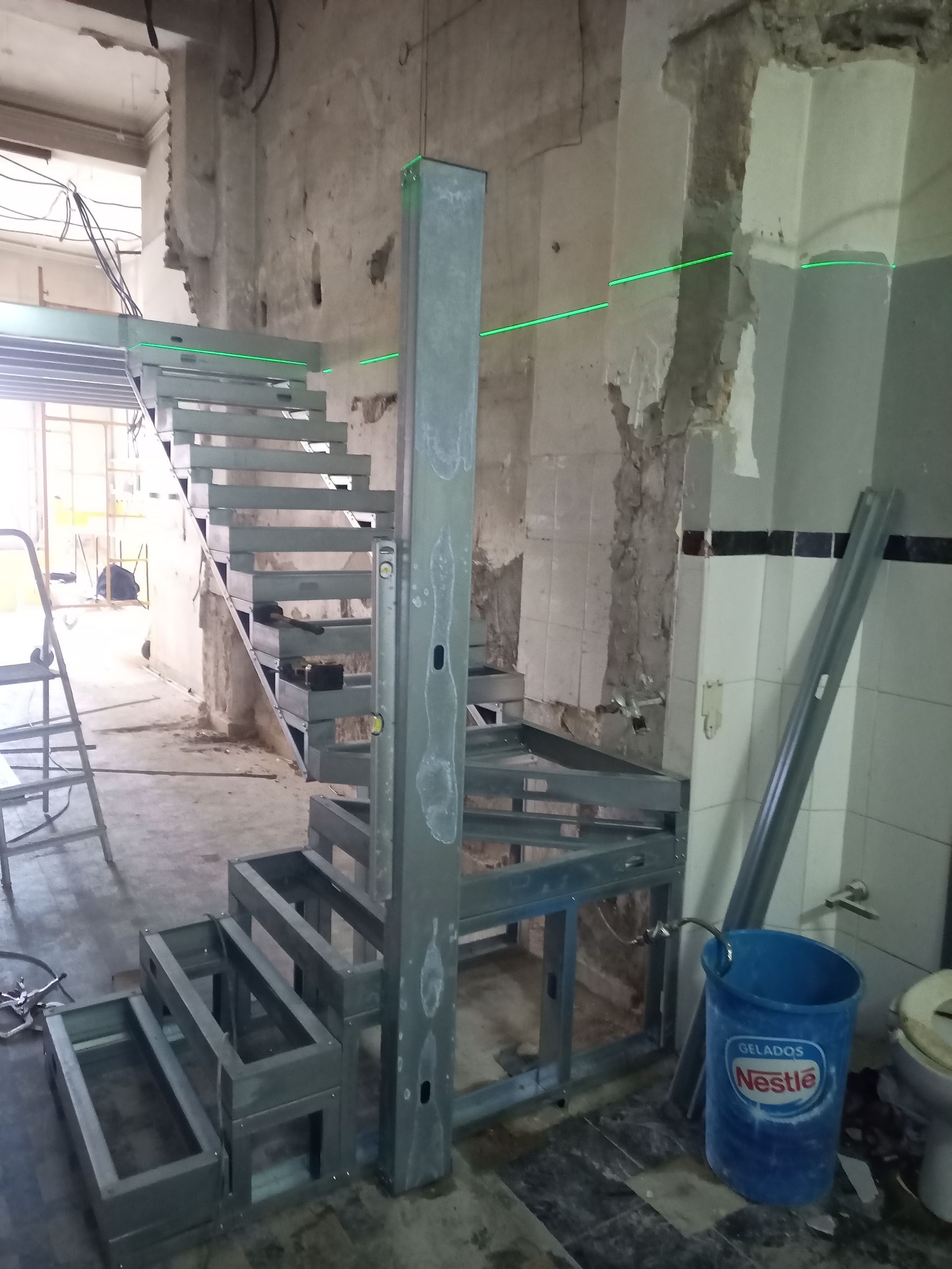 Escada metálica em construção em um cômodo inacabado. A estrutura da escada está soldada.