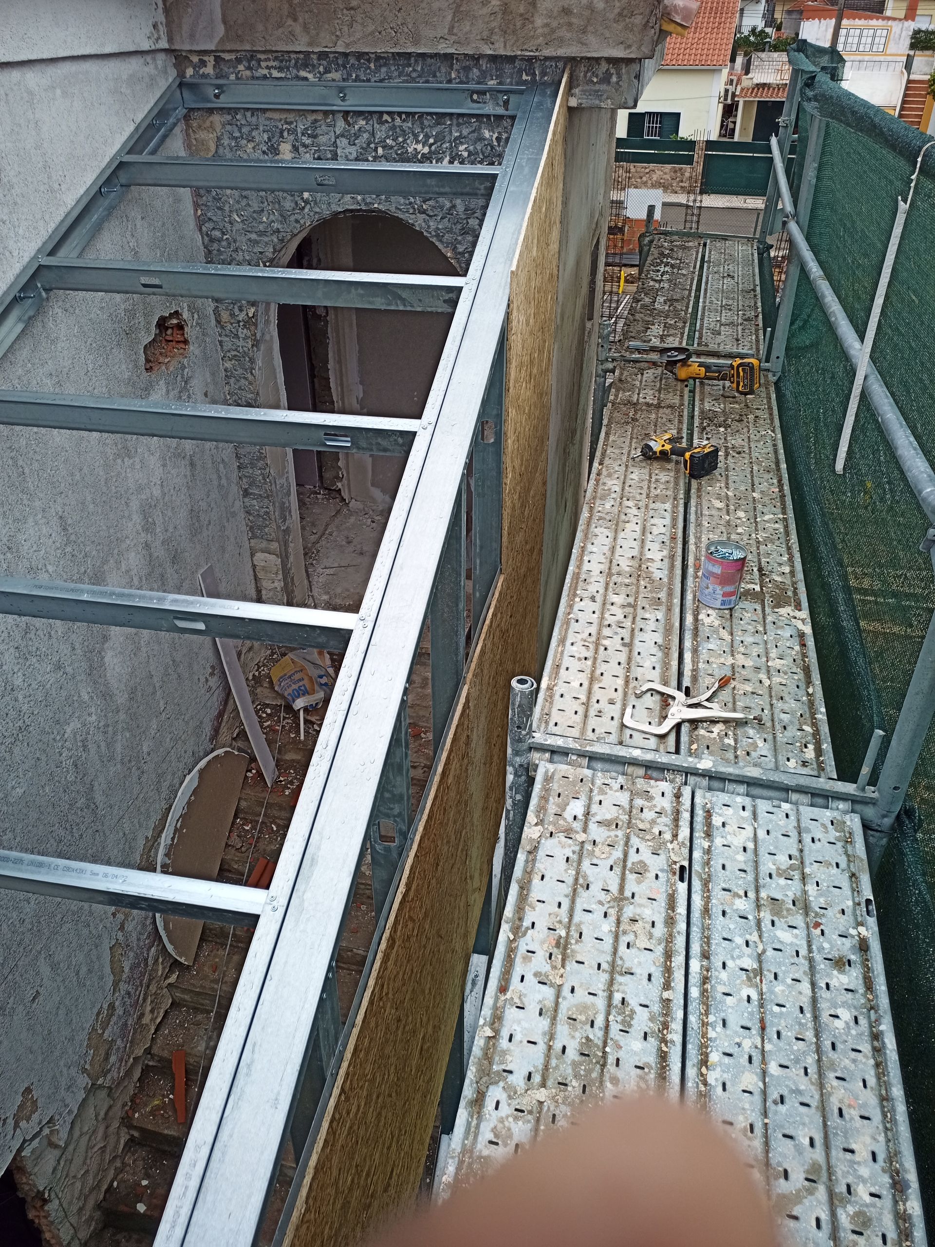 Andaimes metálicos ao lado de um prédio em construção. Estrutura metálica cinza visível.