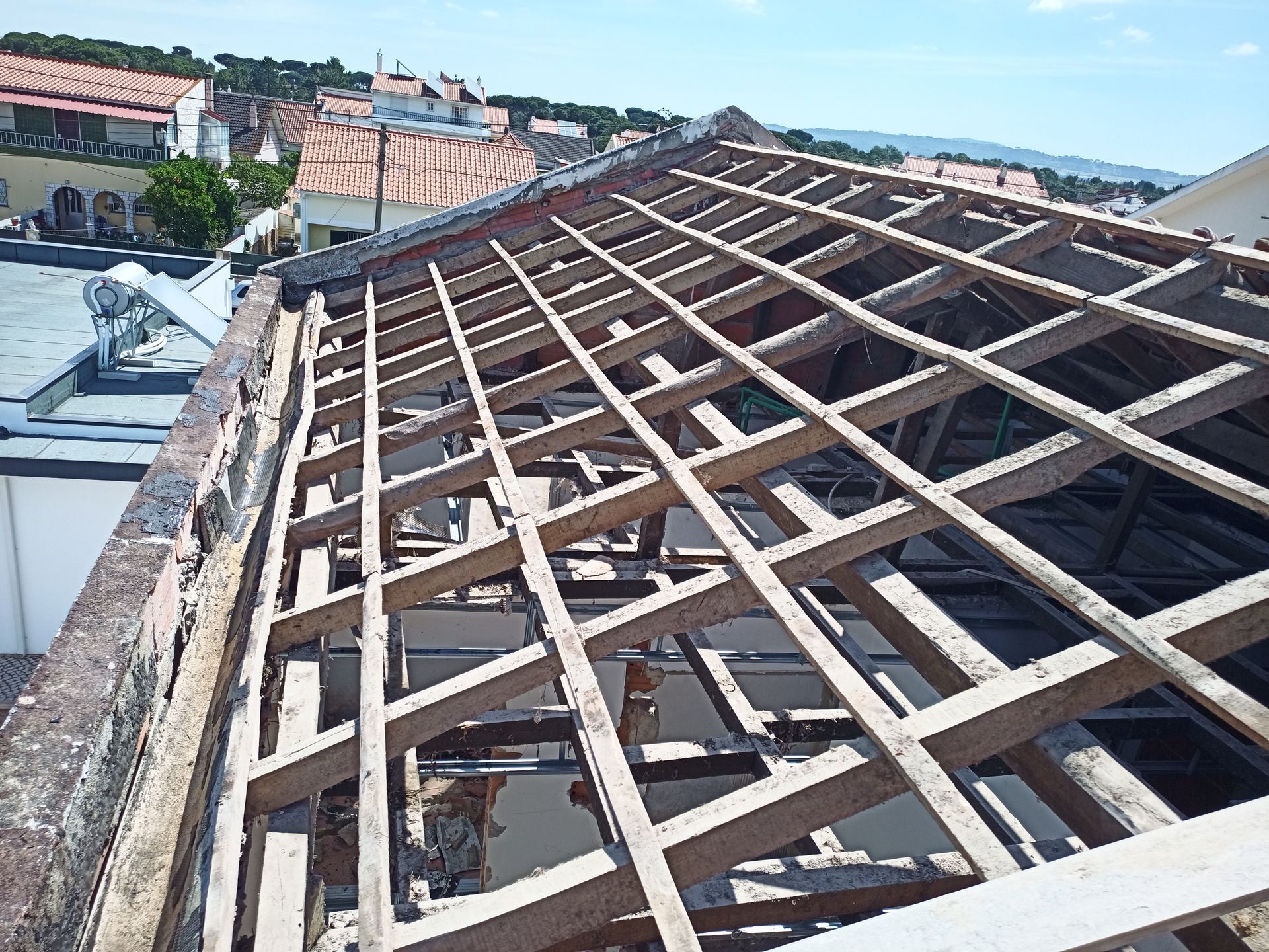 Estrutura de telhado de madeira em construção com paisagem urbana ao fundo.