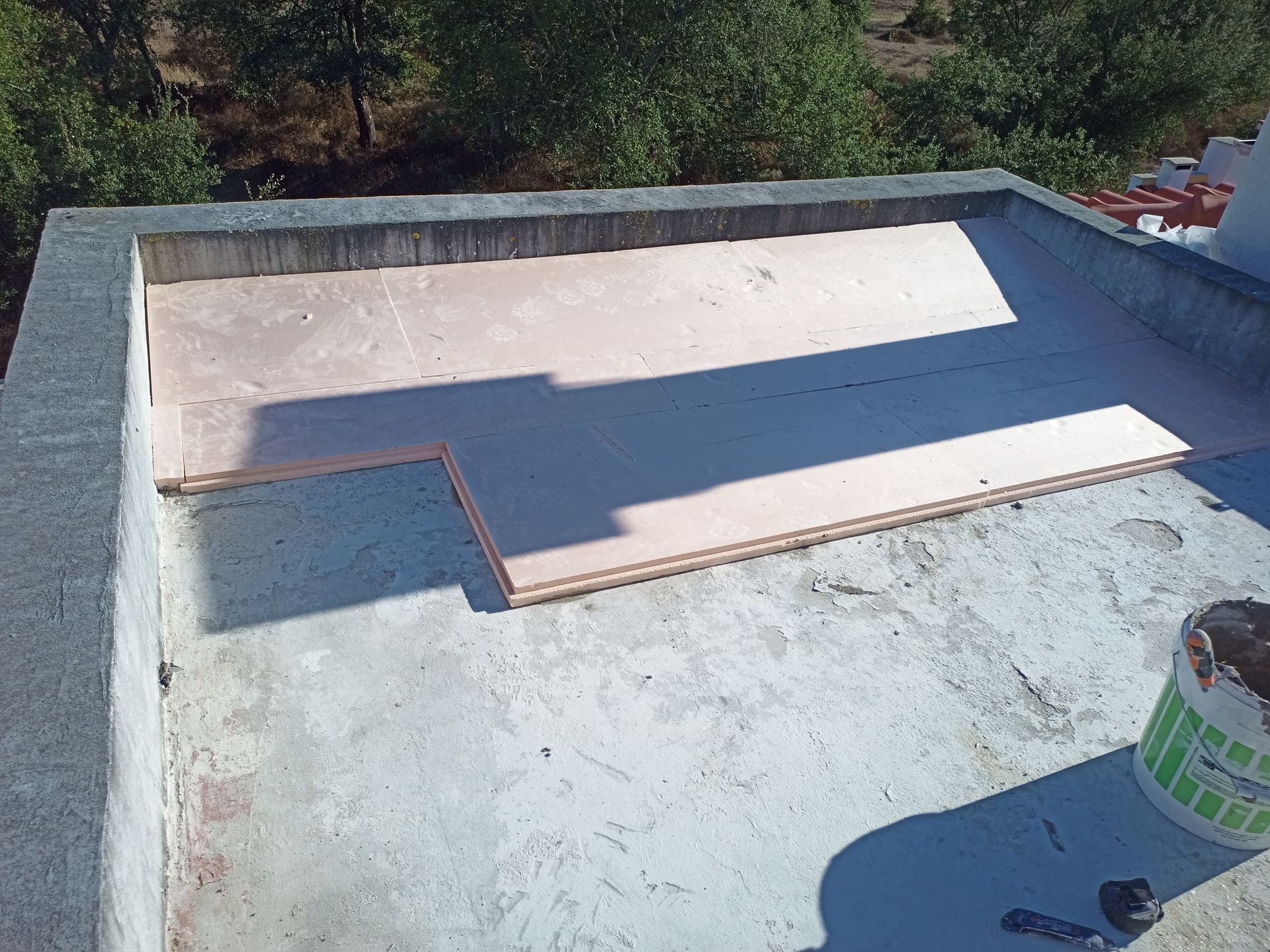 Telhado plano em construção com painéis de isolamento rosa parcialmente instalados.