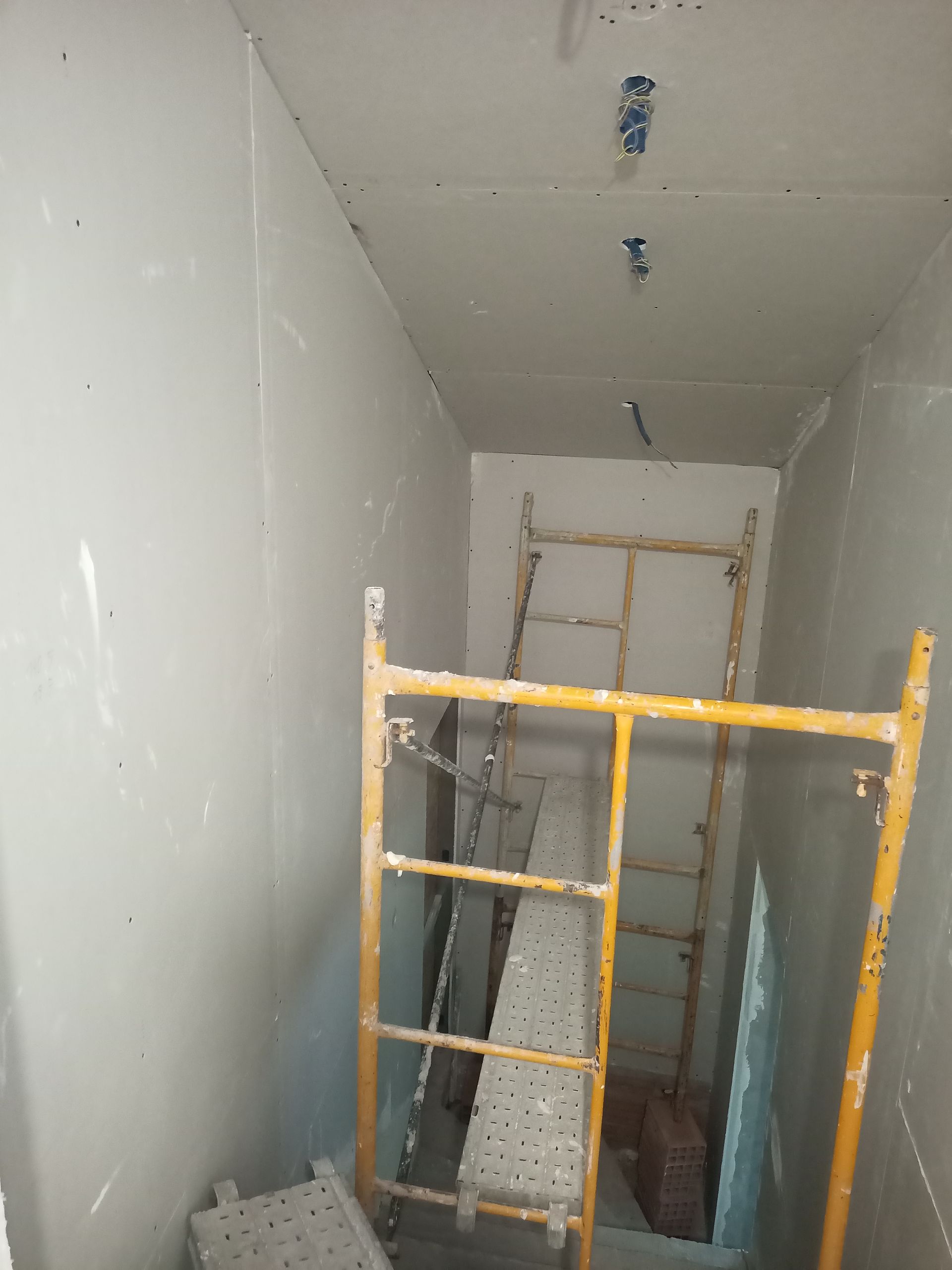 Construção de interiores com paredes de gesso cartonado, andaimes e instalações elétricas.