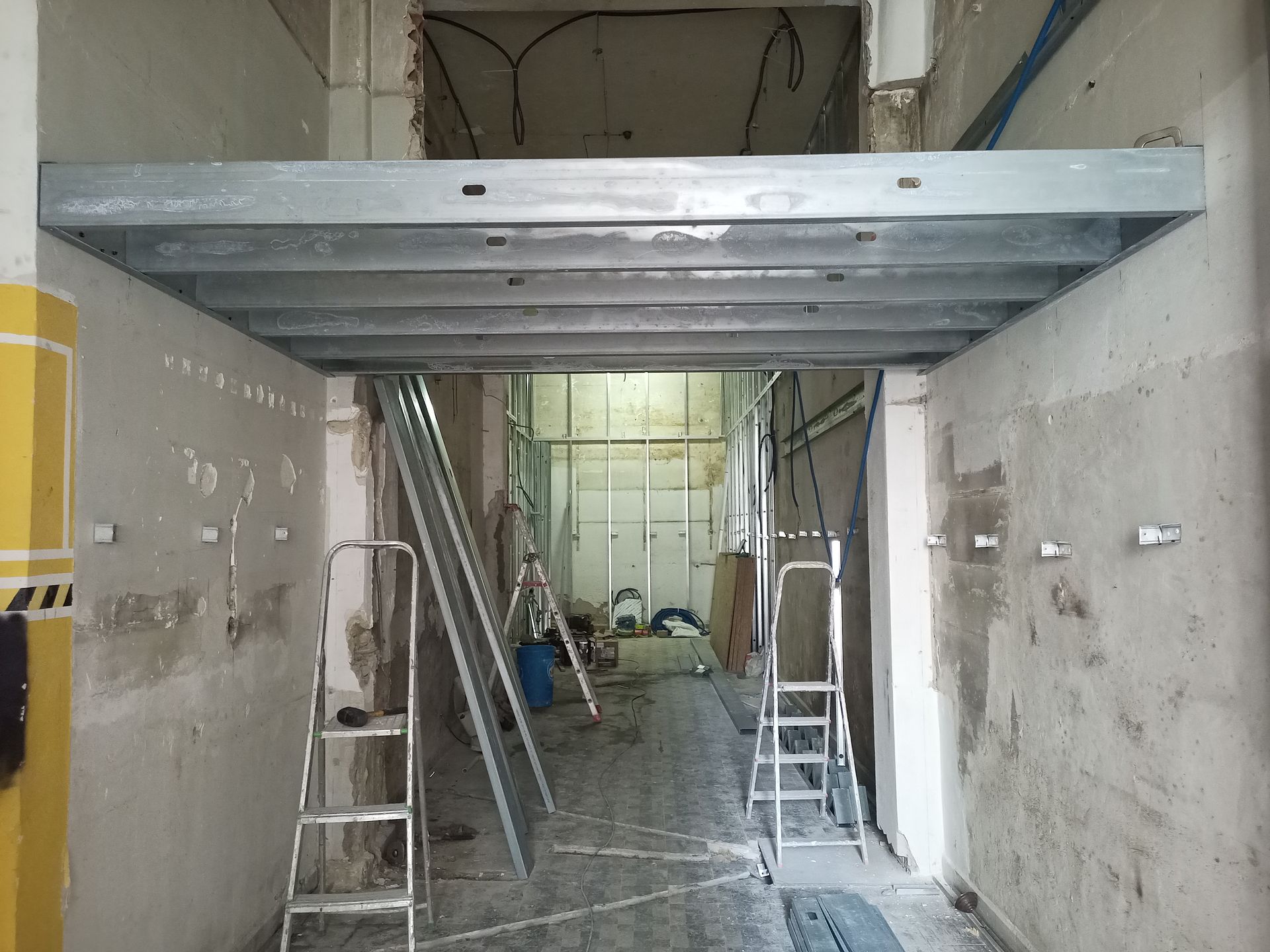 Estrutura metálica instalada em uma porta durante a construção. Escadas e entulho da obra são visíveis no cômodo.