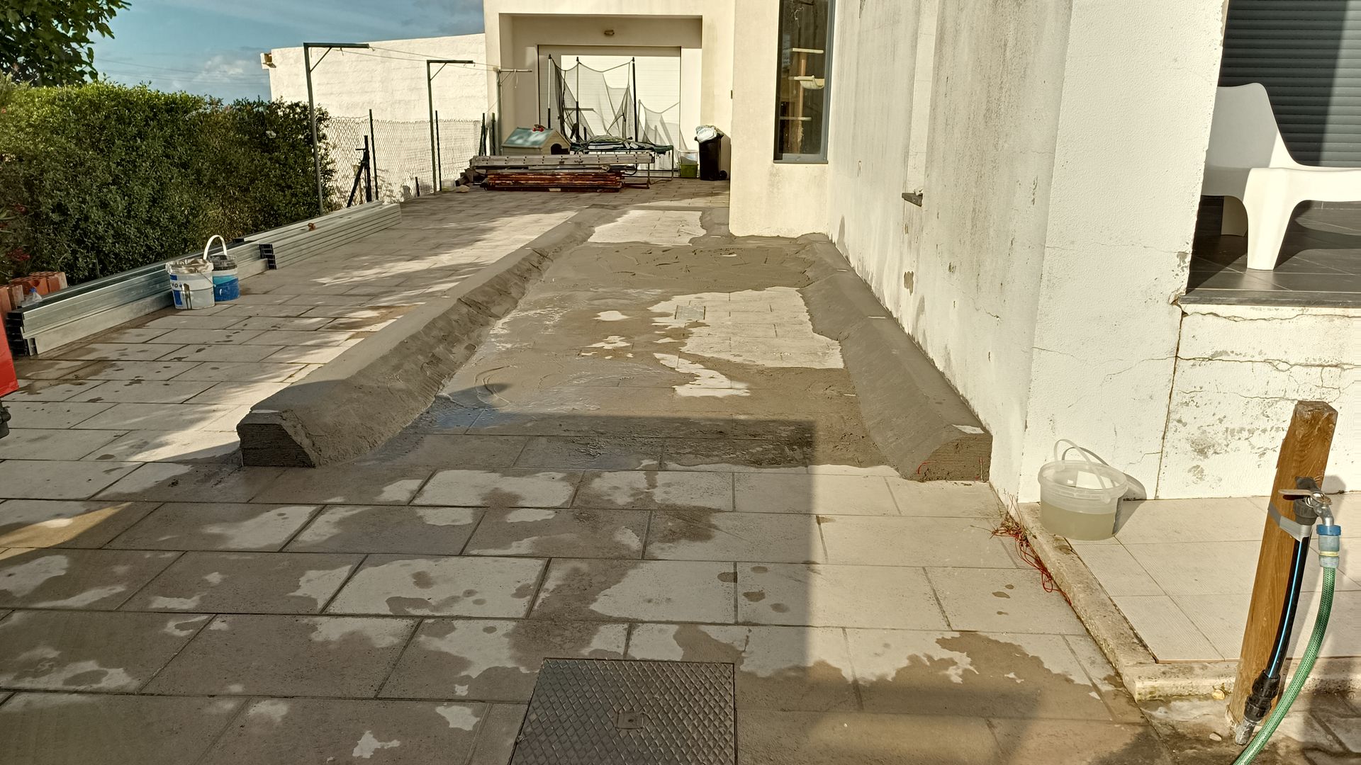 Canteiro de obras com concreto fresco, pedras de pavimentação e construção.