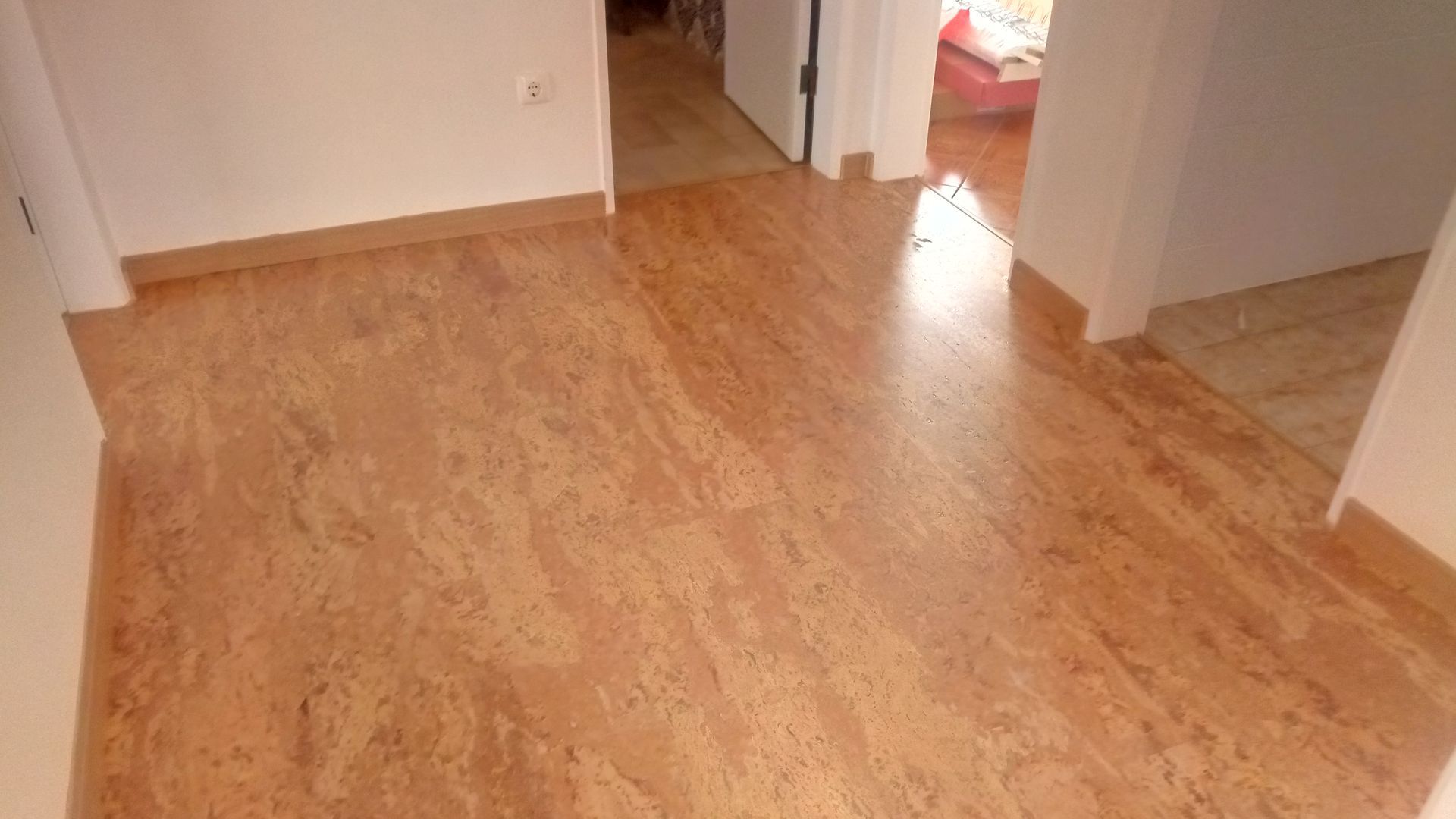 Corredor com piso marrom-avermelhado e paredes brancas.