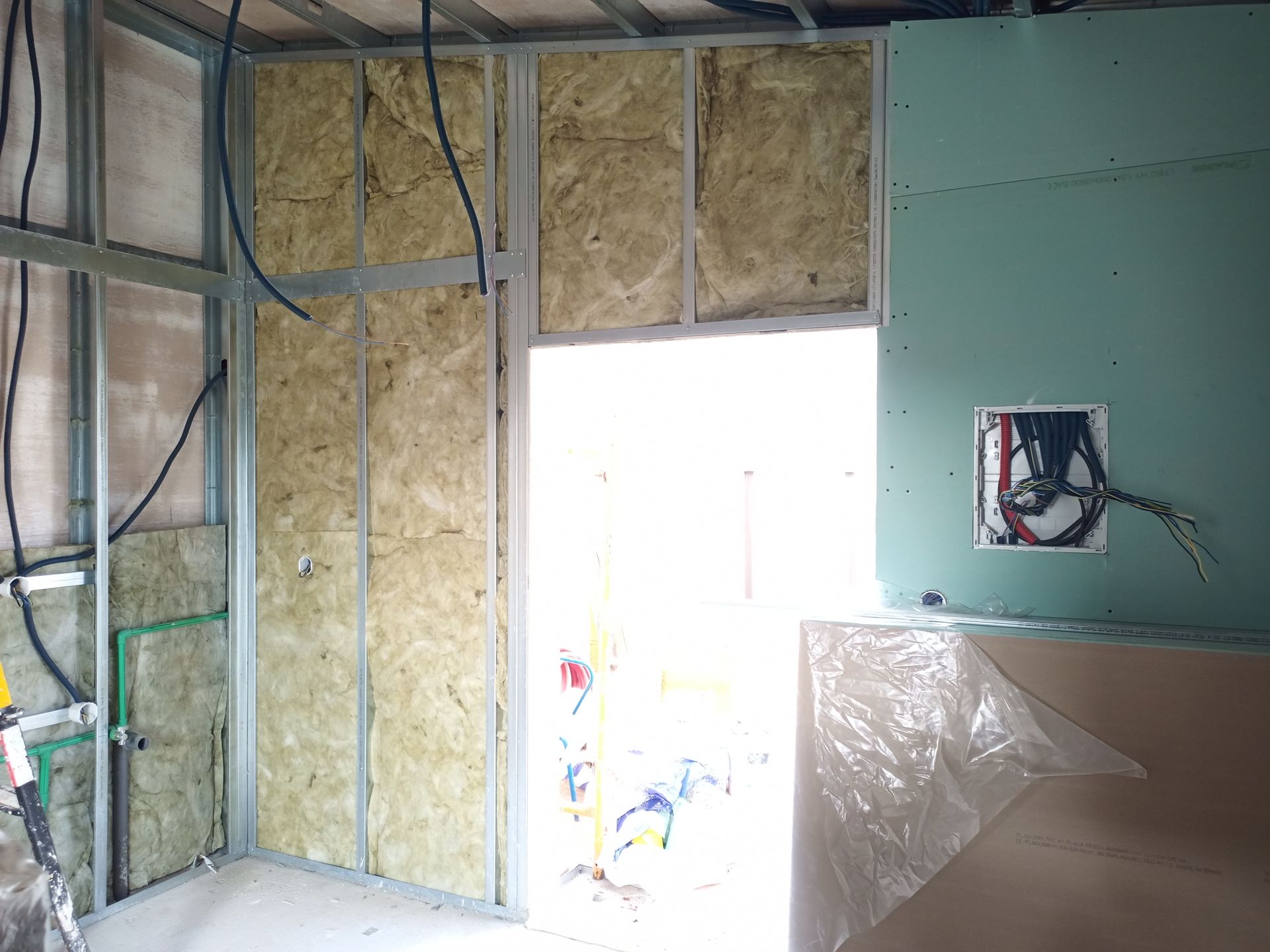 Parede interna em construção com isolamento e drywall.