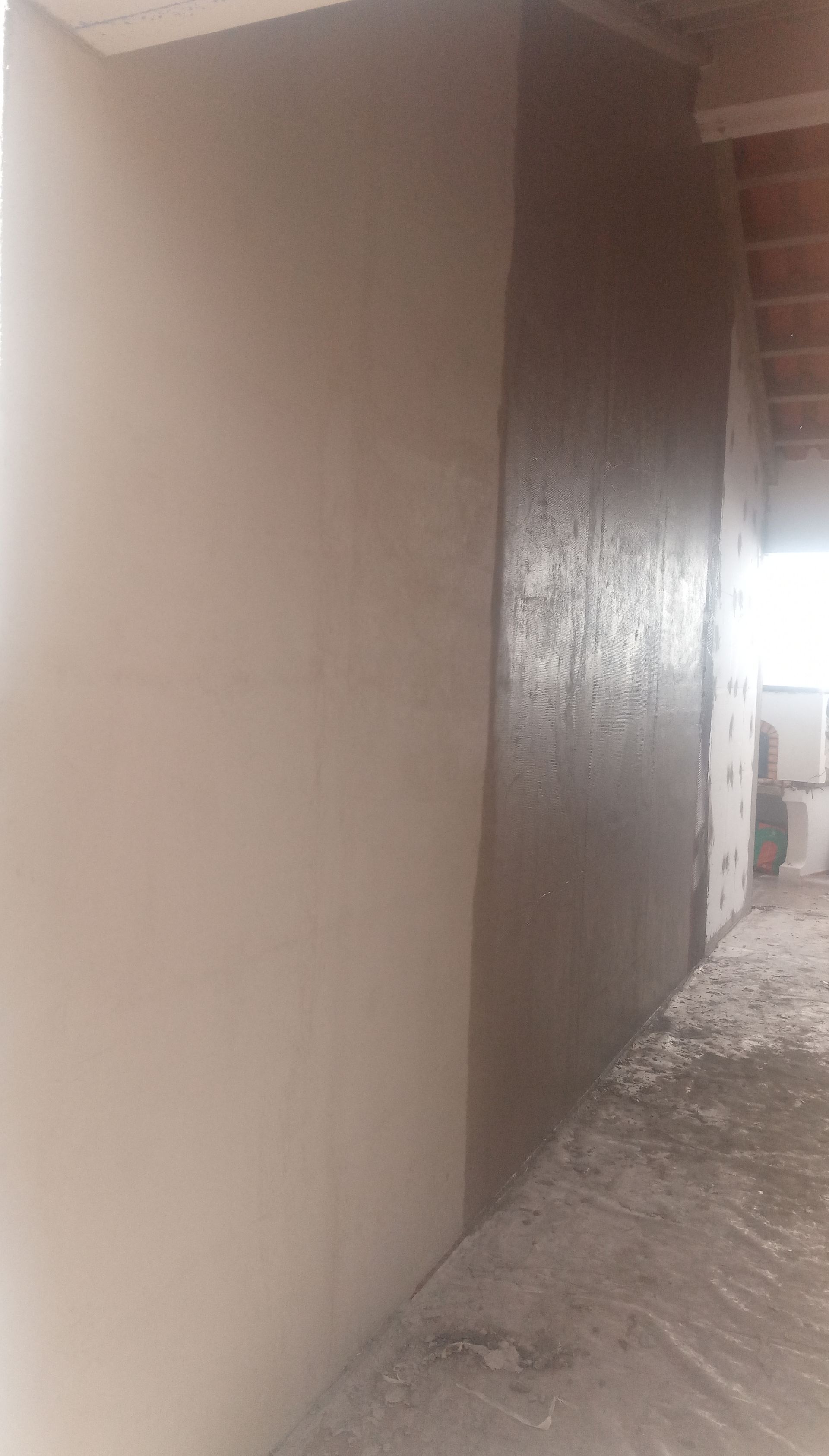 Duas paredes adjacentes, uma lisa e clara, a outra áspera e escura, em um contexto de construção.