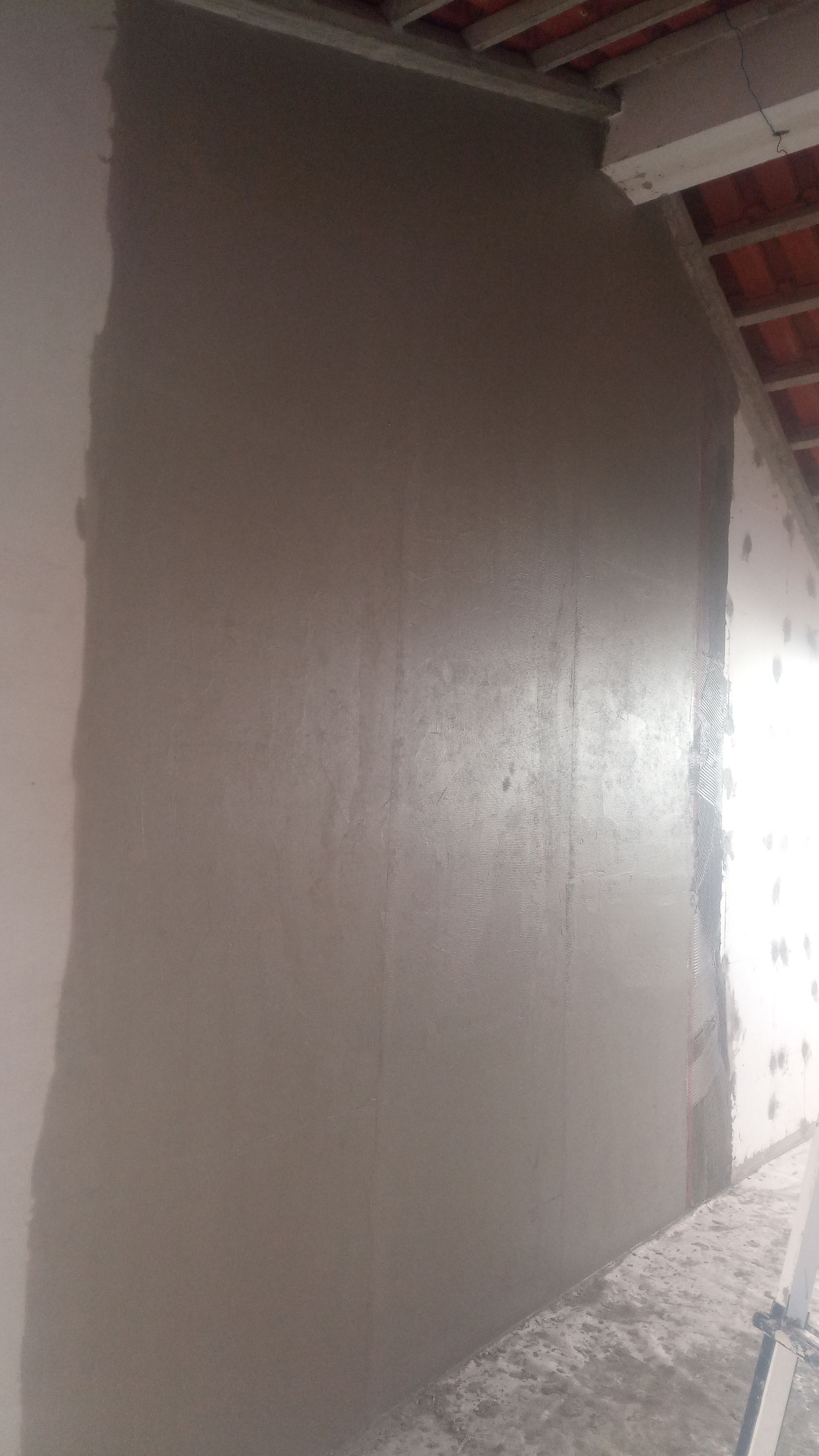 Gesso cinza aplicado em uma parede, possivelmente em um projeto de reforma.