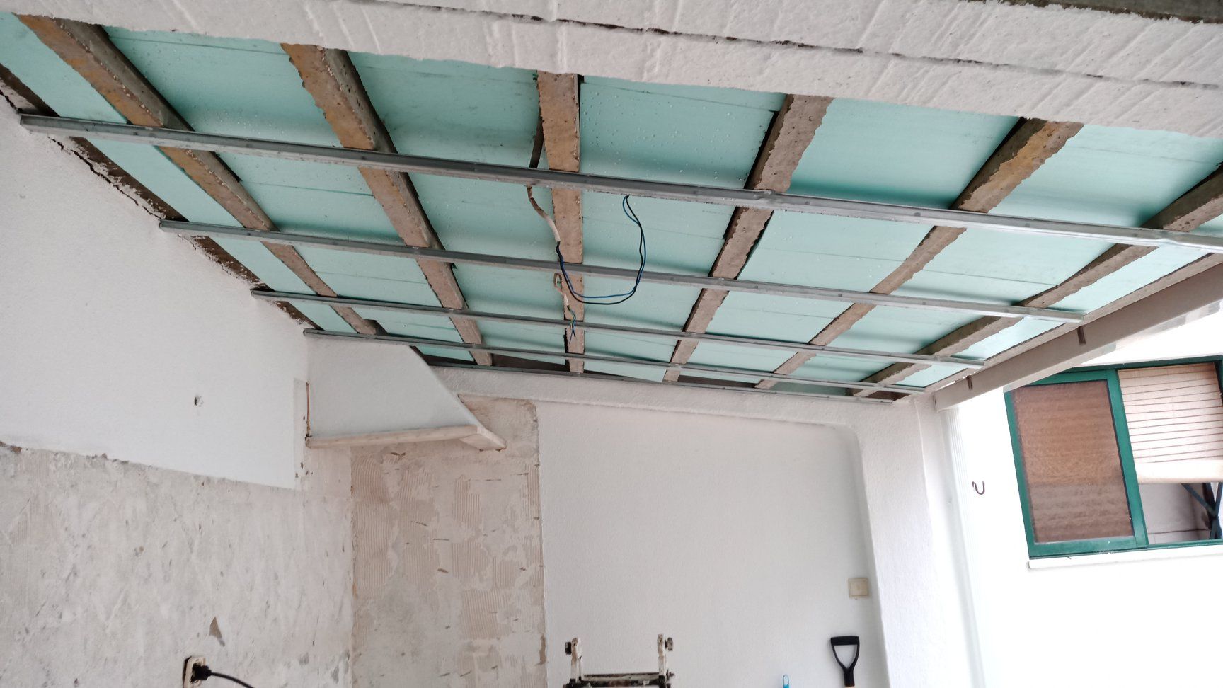 Teto em construção com vigas de madeira, isolamento e estrutura metálica.