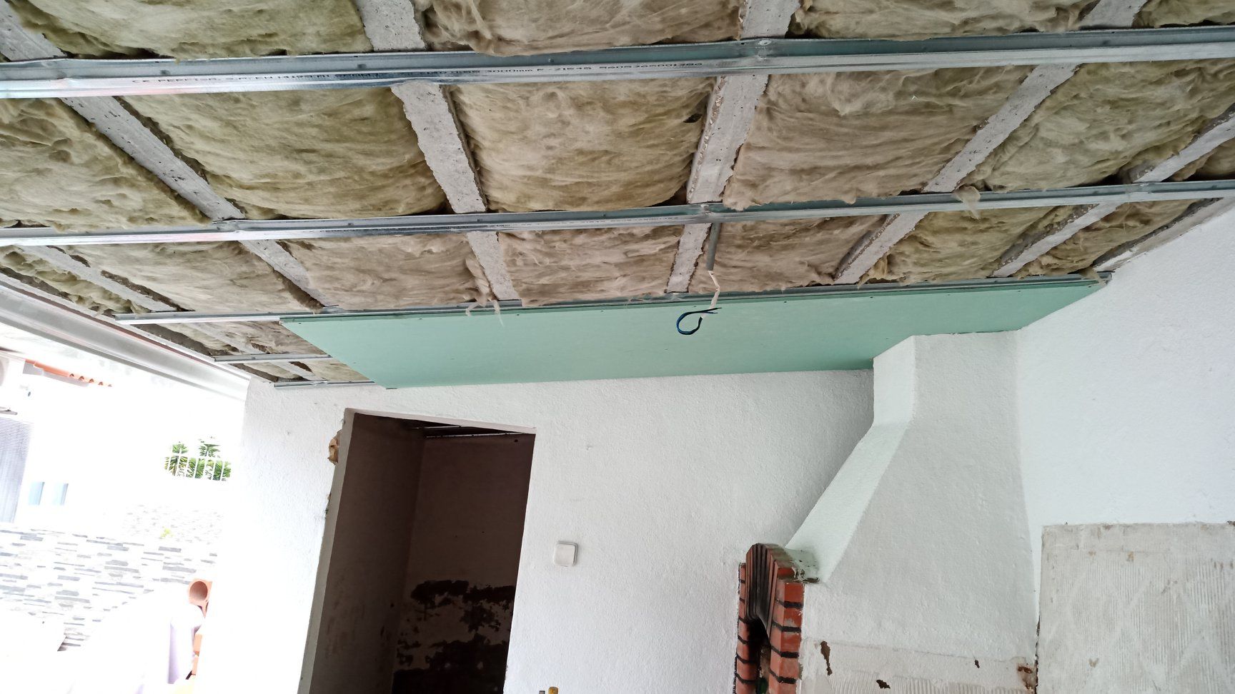 Estrutura do teto: estrutura metálica com isolamento, parcialmente revestida por drywall verde. Vista interna.