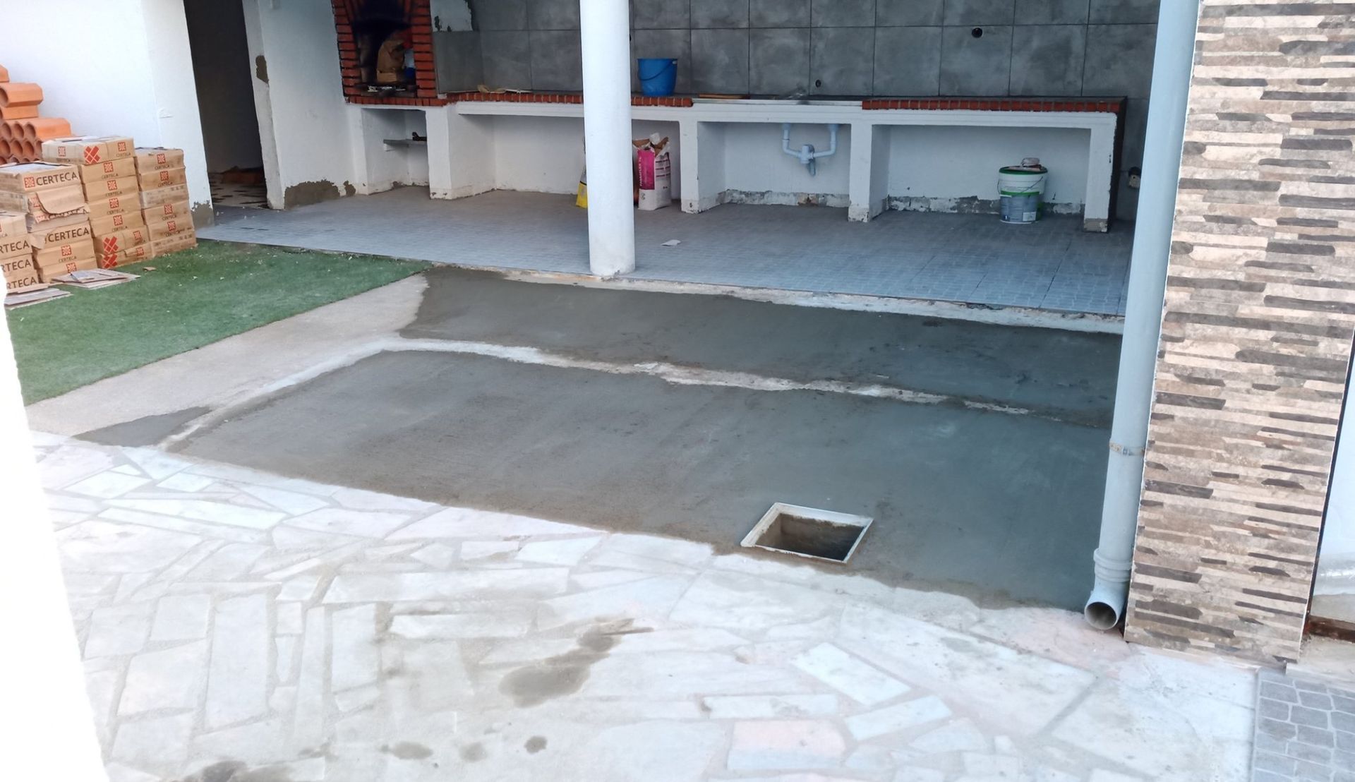 Cozinha externa em construção, com concreto e alvenaria recém-moldados.
