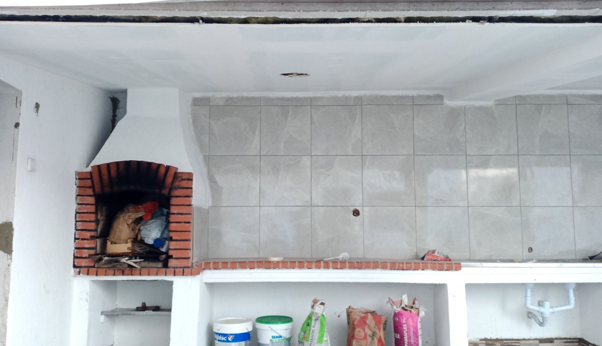 Cozinha externa com lareira de tijolos, backsplash de azulejos e armários embutidos.