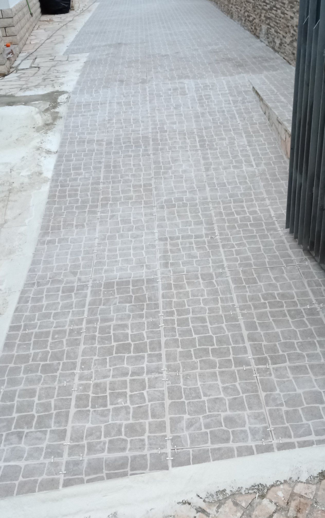 Caminho de paralelepípedos com rampa para acessibilidade.