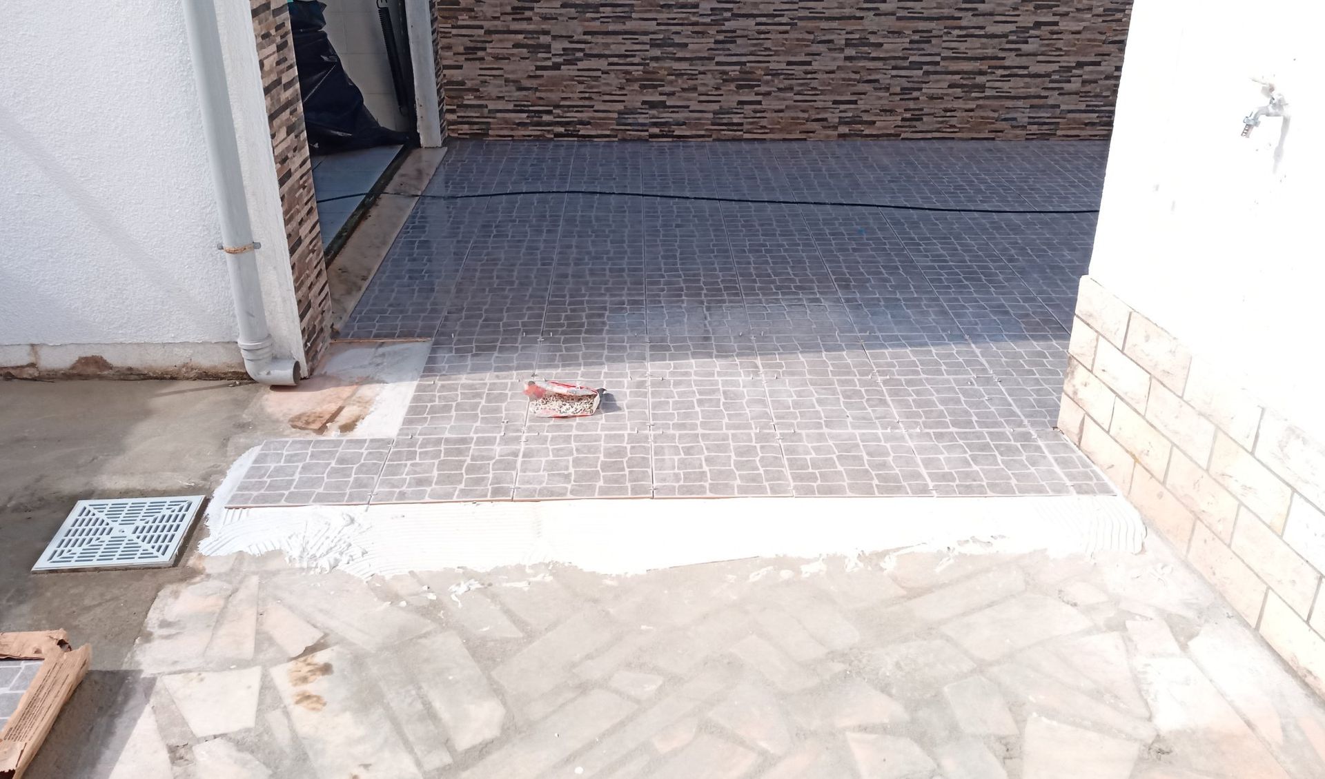 Entrada de automóveis pavimentada com tijolos, acesso à garagem com degrau, edifício.