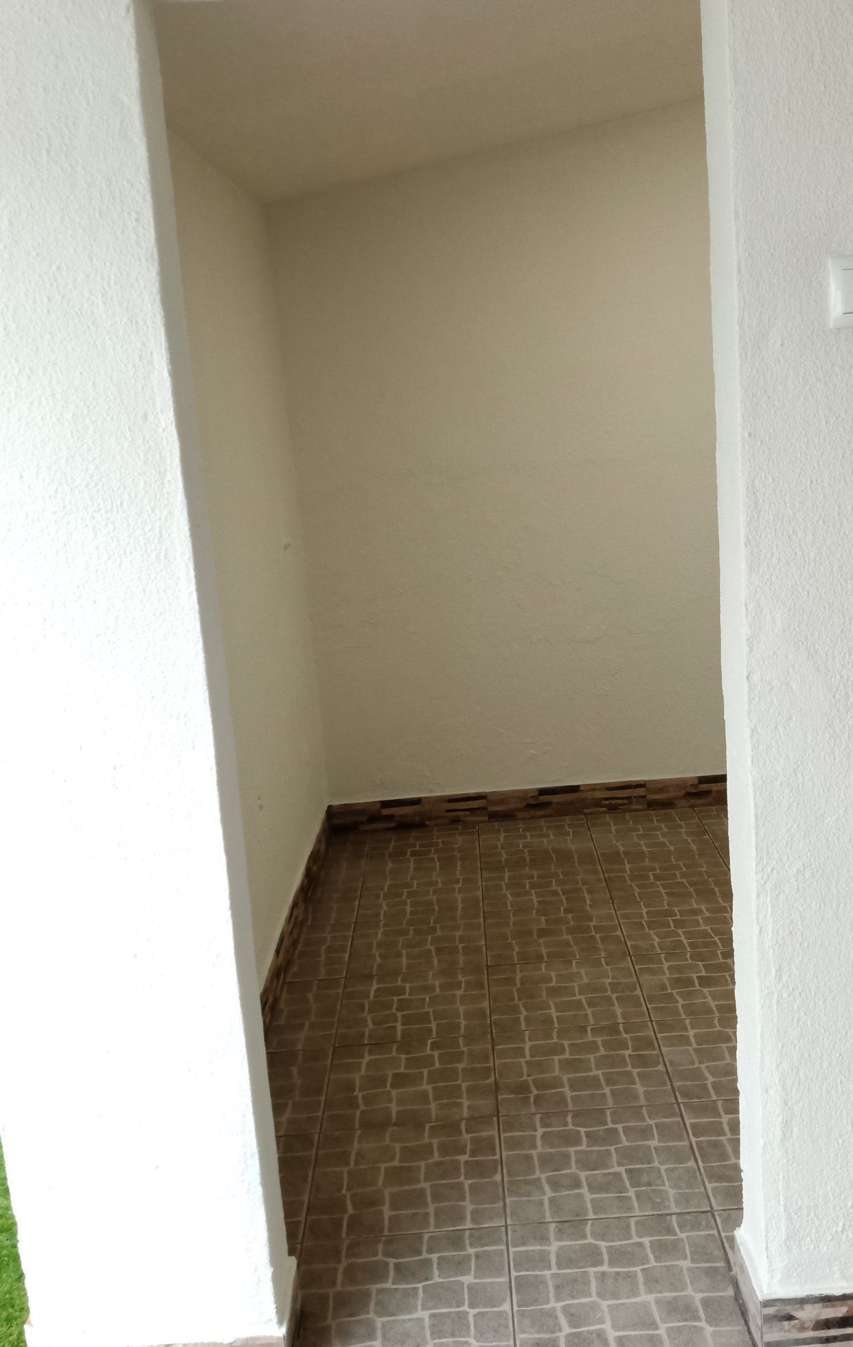 Um pequeno nicho vazio com paredes bege e piso de azulejos.