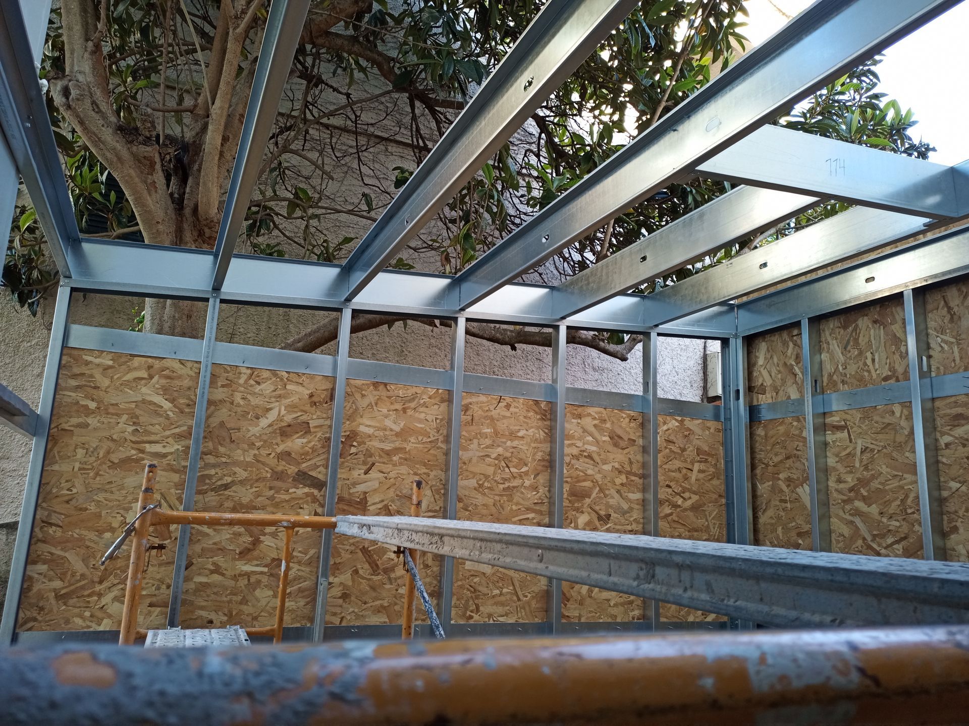 Estrutura metálica com painéis de madeira; canteiro de obras.