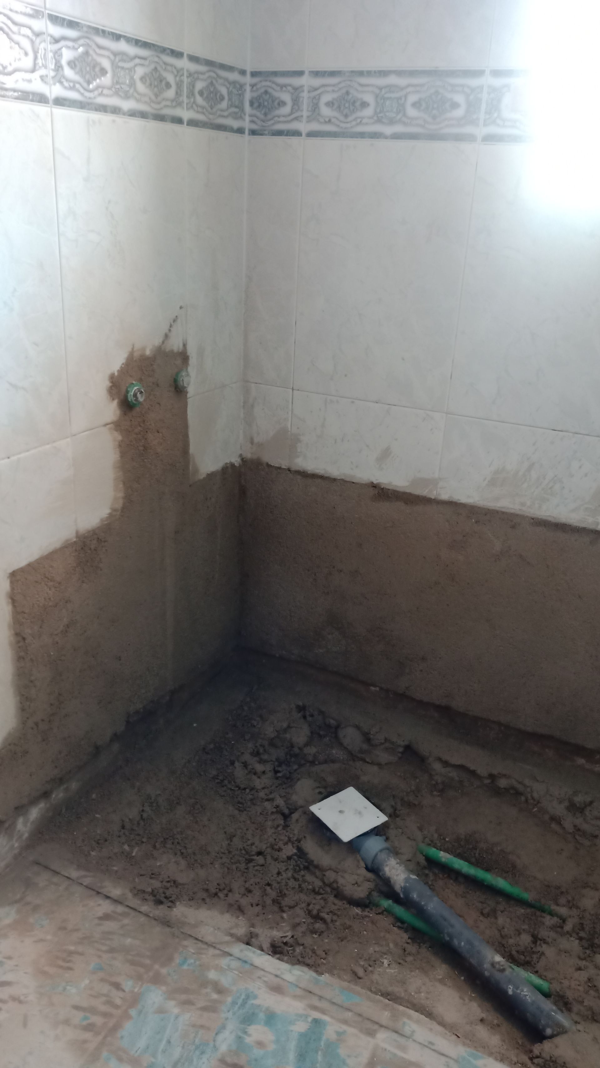 Banheiro em construção, com encanamento aparente e paredes inacabadas.