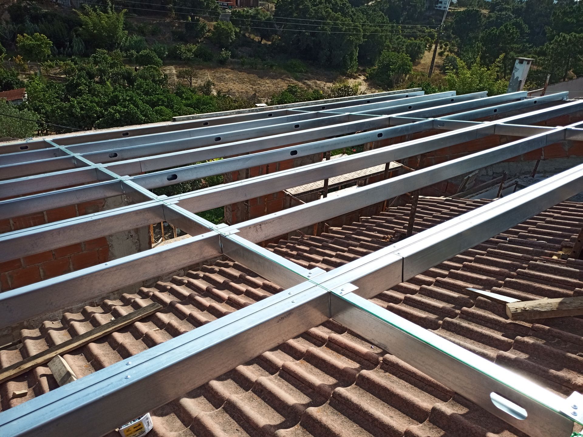 Estrutura metálica instalada em telhado de telhas, preparada para a instalação de painéis solares.