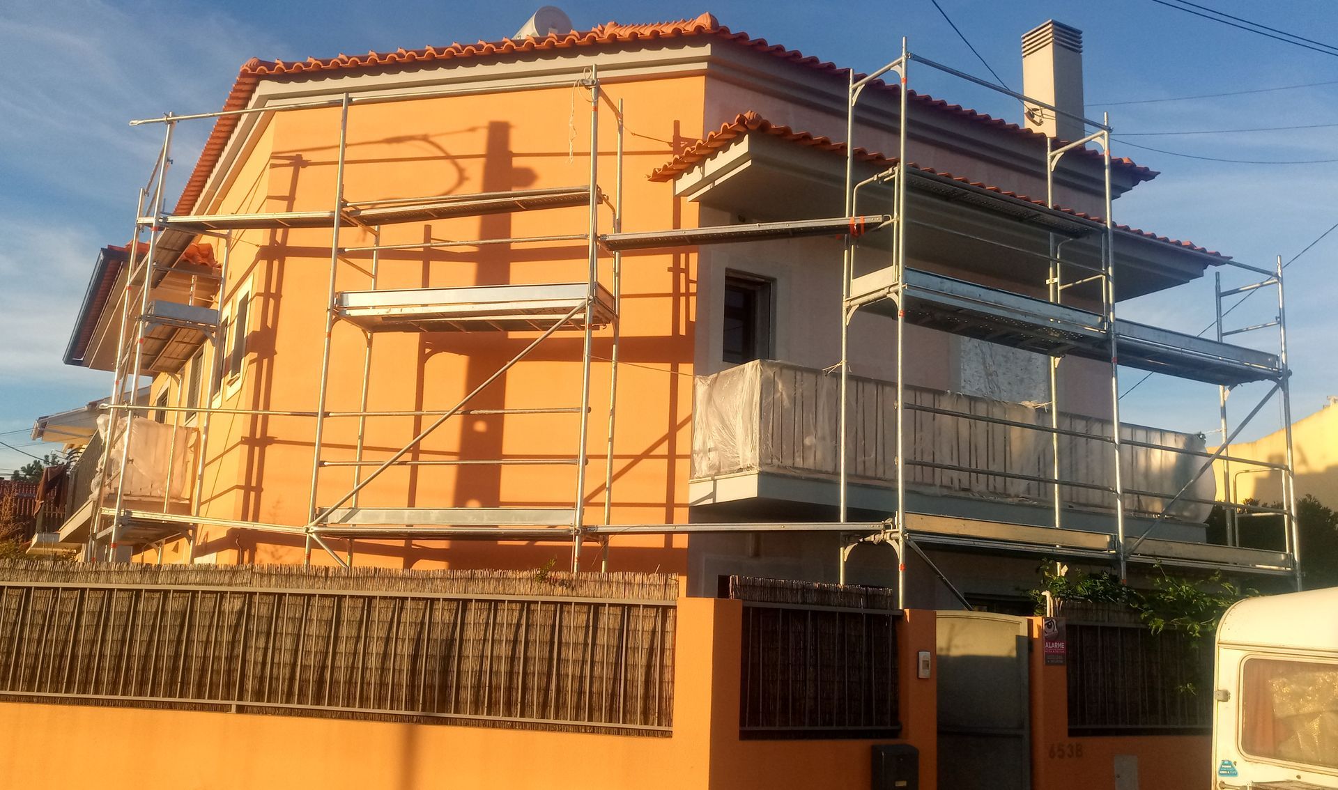 Casa laranja com andaimes, em reforma.