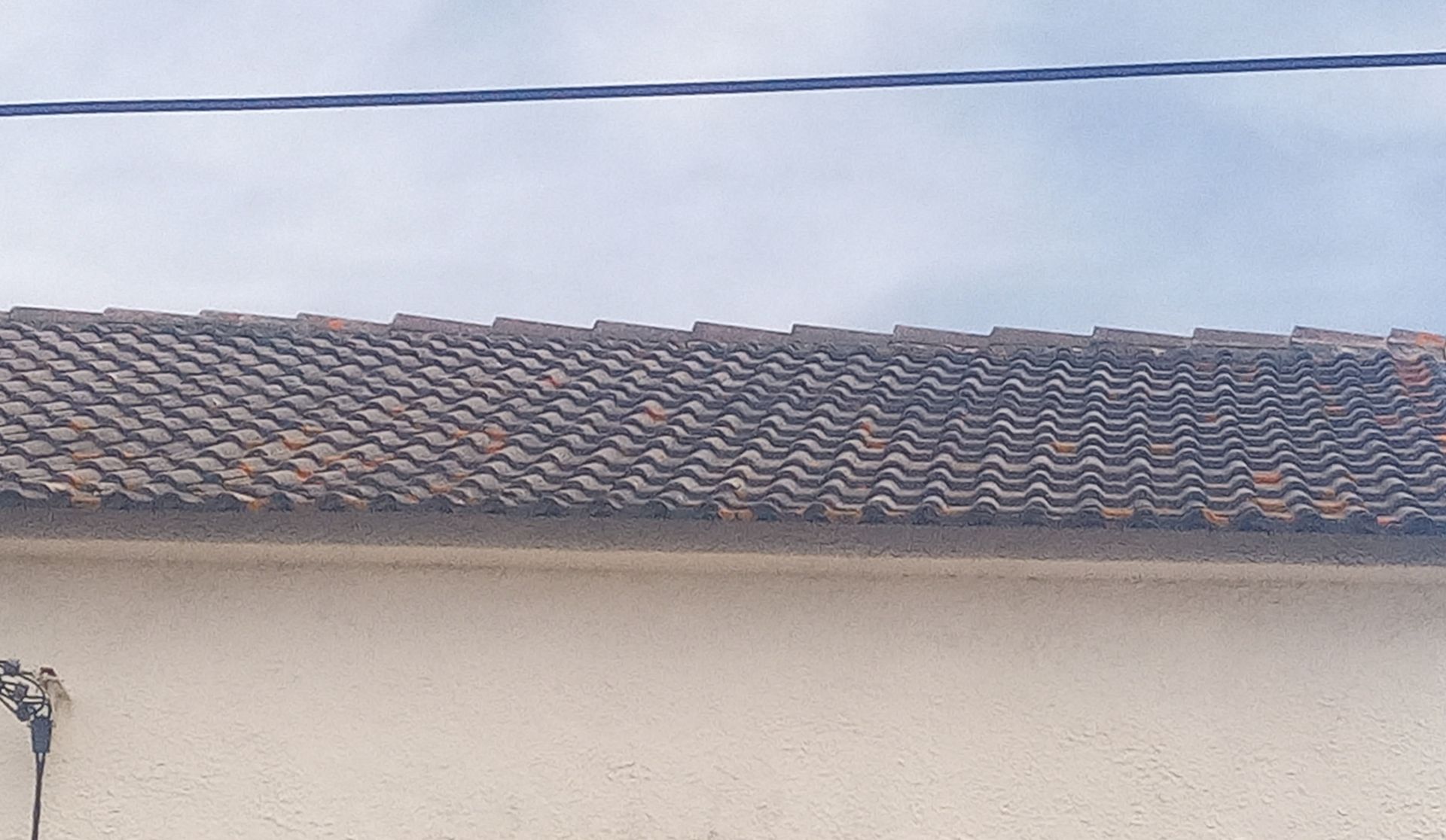 Telhado de um prédio com telhas marrons contra um céu nublado.