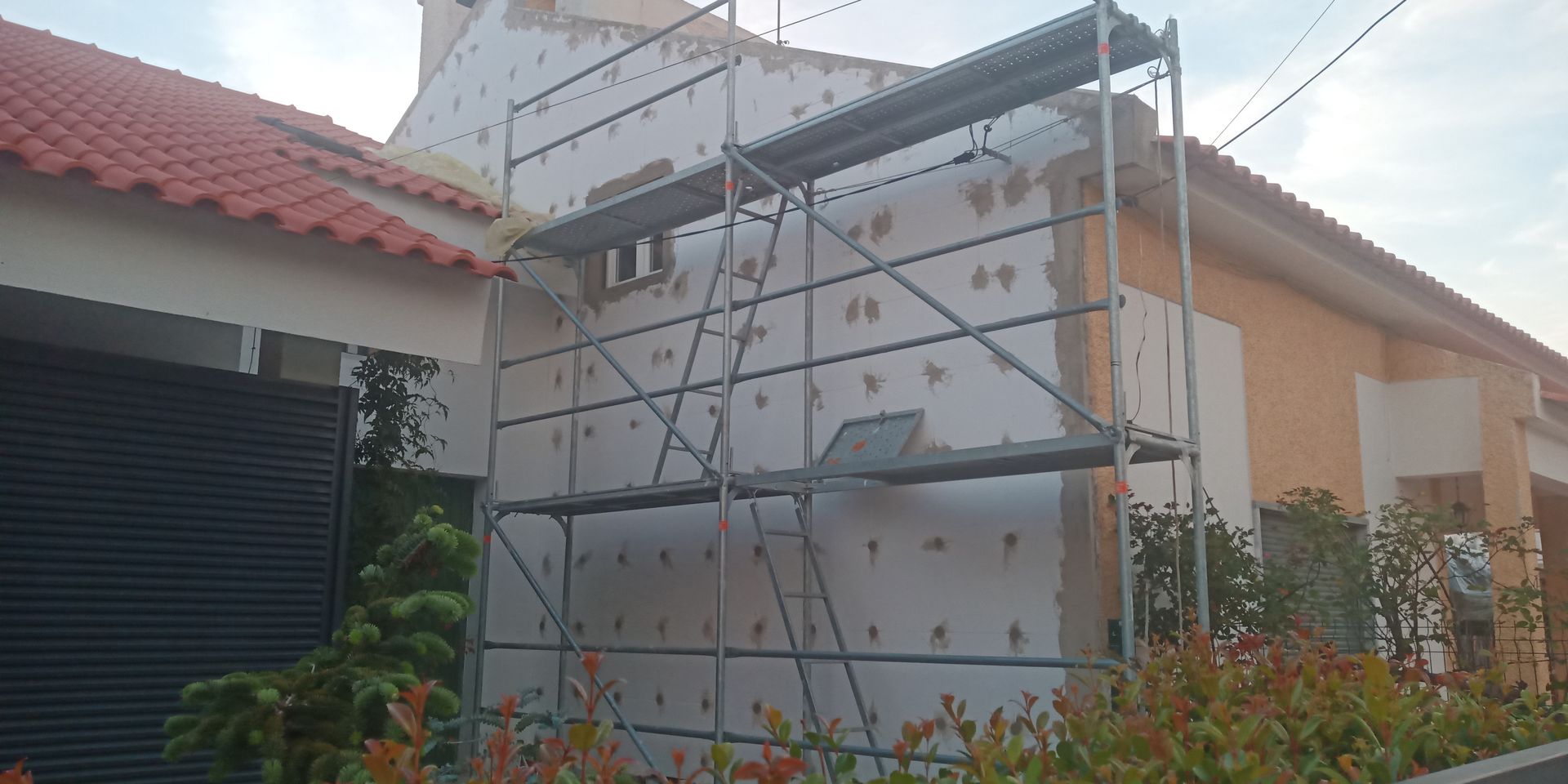 Casa em reforma com andaimes e painéis de isolamento expostos.